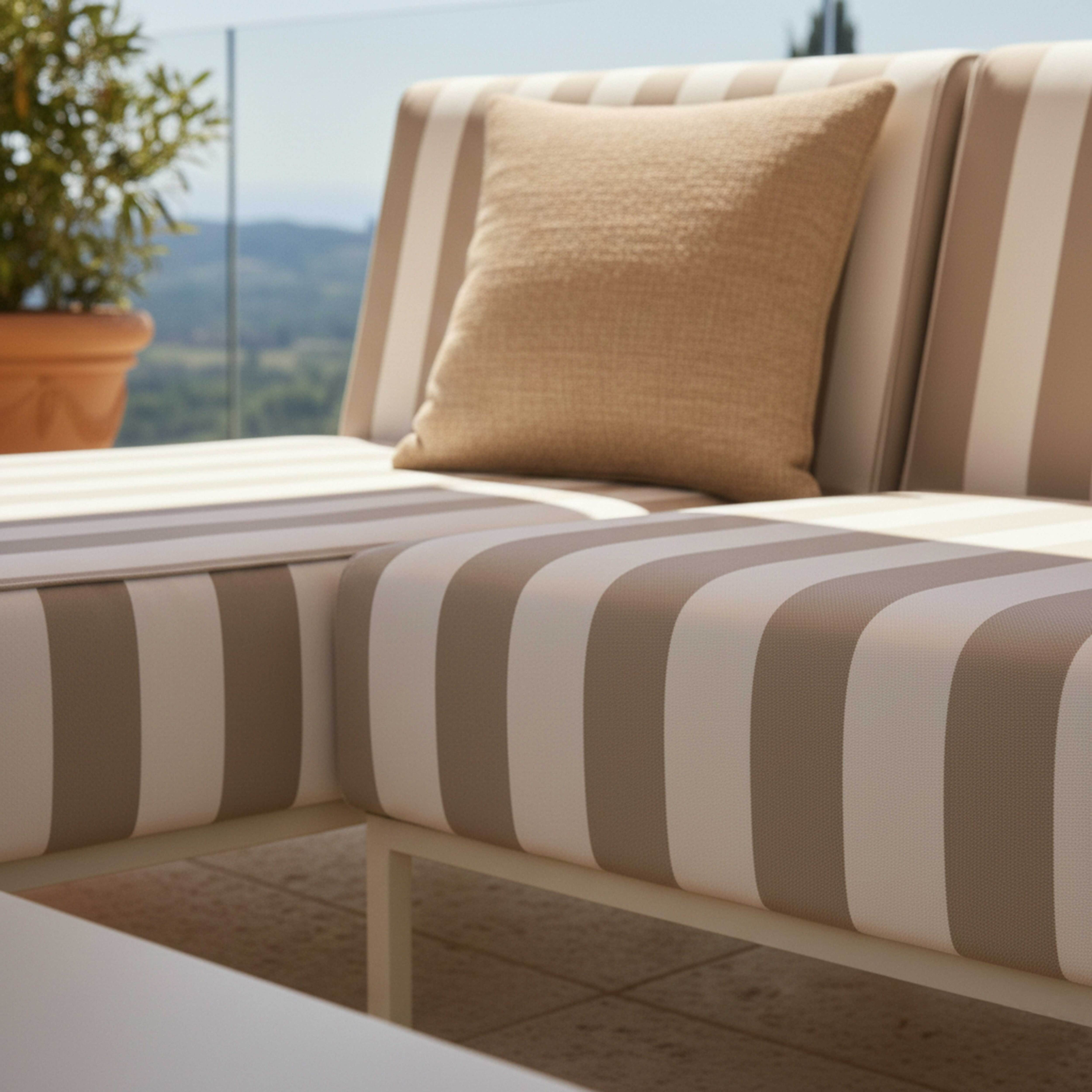 Ein gestreiftes Outdoor-Sofa mit einem Kissen draußen mit Blick auf Hügel.