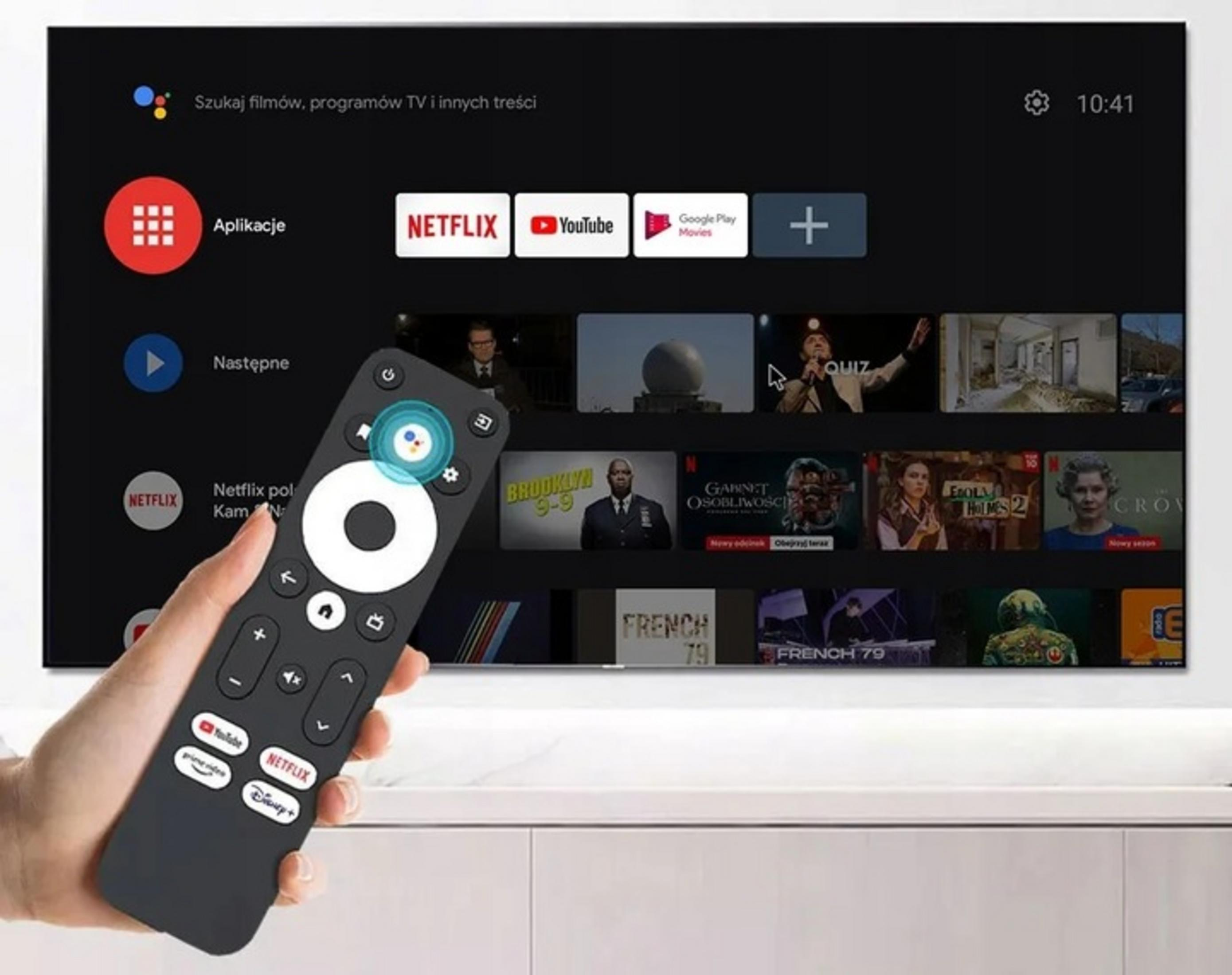 Una mano tiene un telecomando davanti a uno schermo Smart TV che mostra le app.