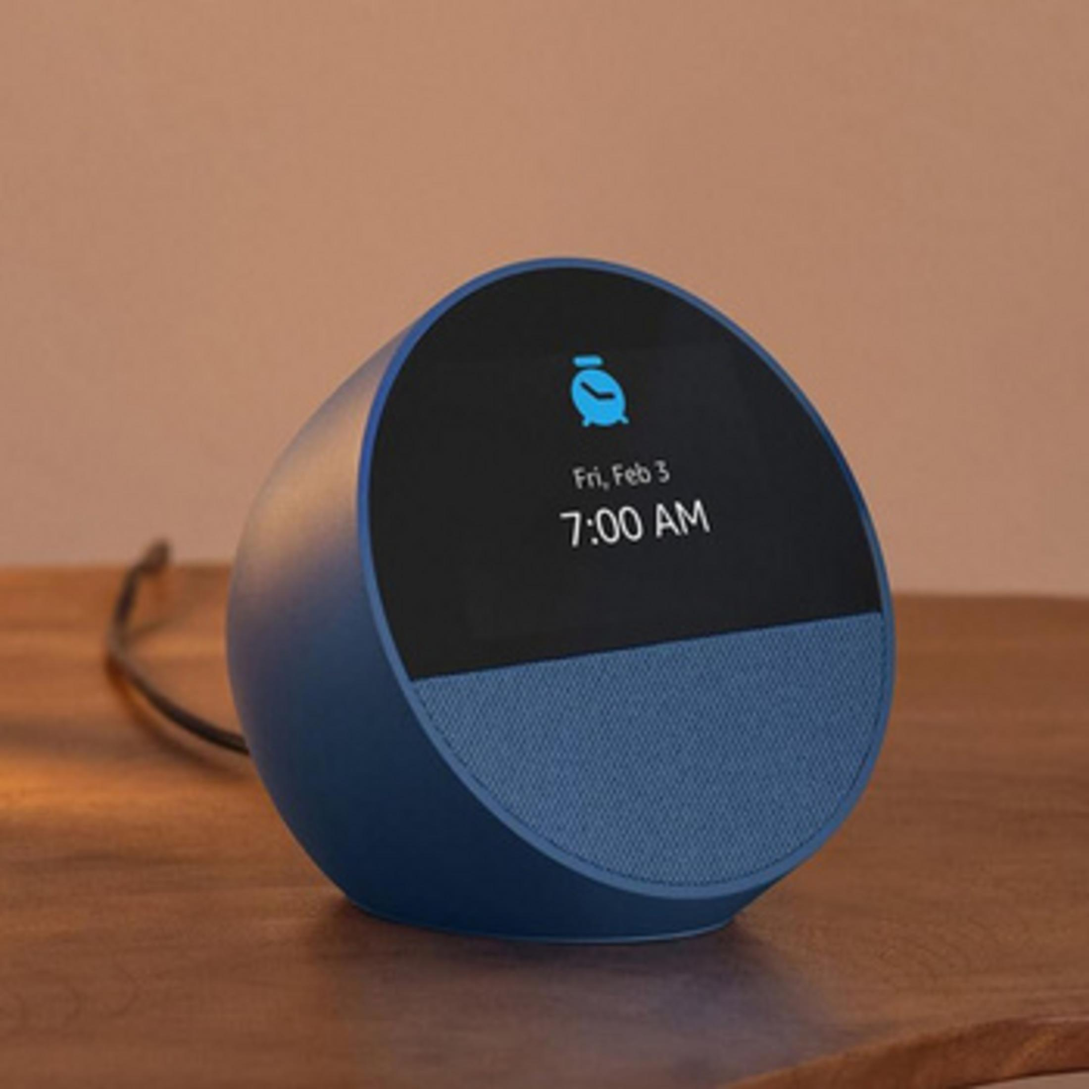 Niebieski głośnik inteligentny z czarnym ekranem pokazującym 7:00.