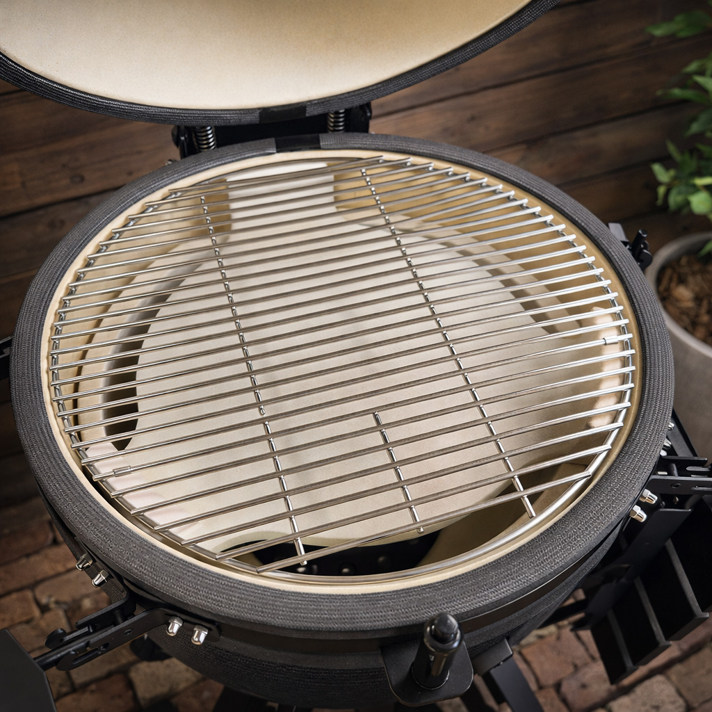 Close-up of a ceramic grill with a metal grate inside. Lid is open.