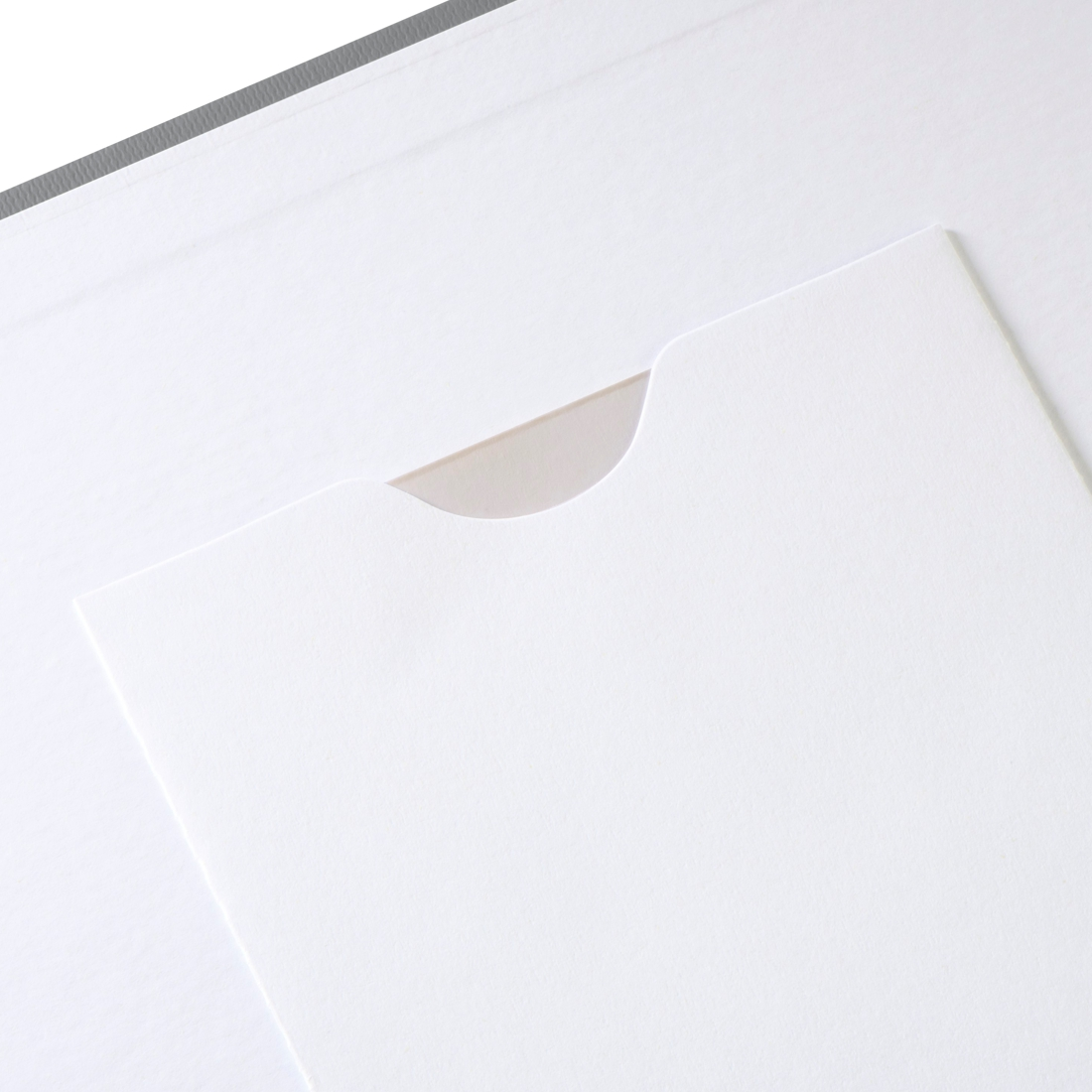Biała papierowa kieszeń z półokrągłym wycięciem i szarym brzegiem.