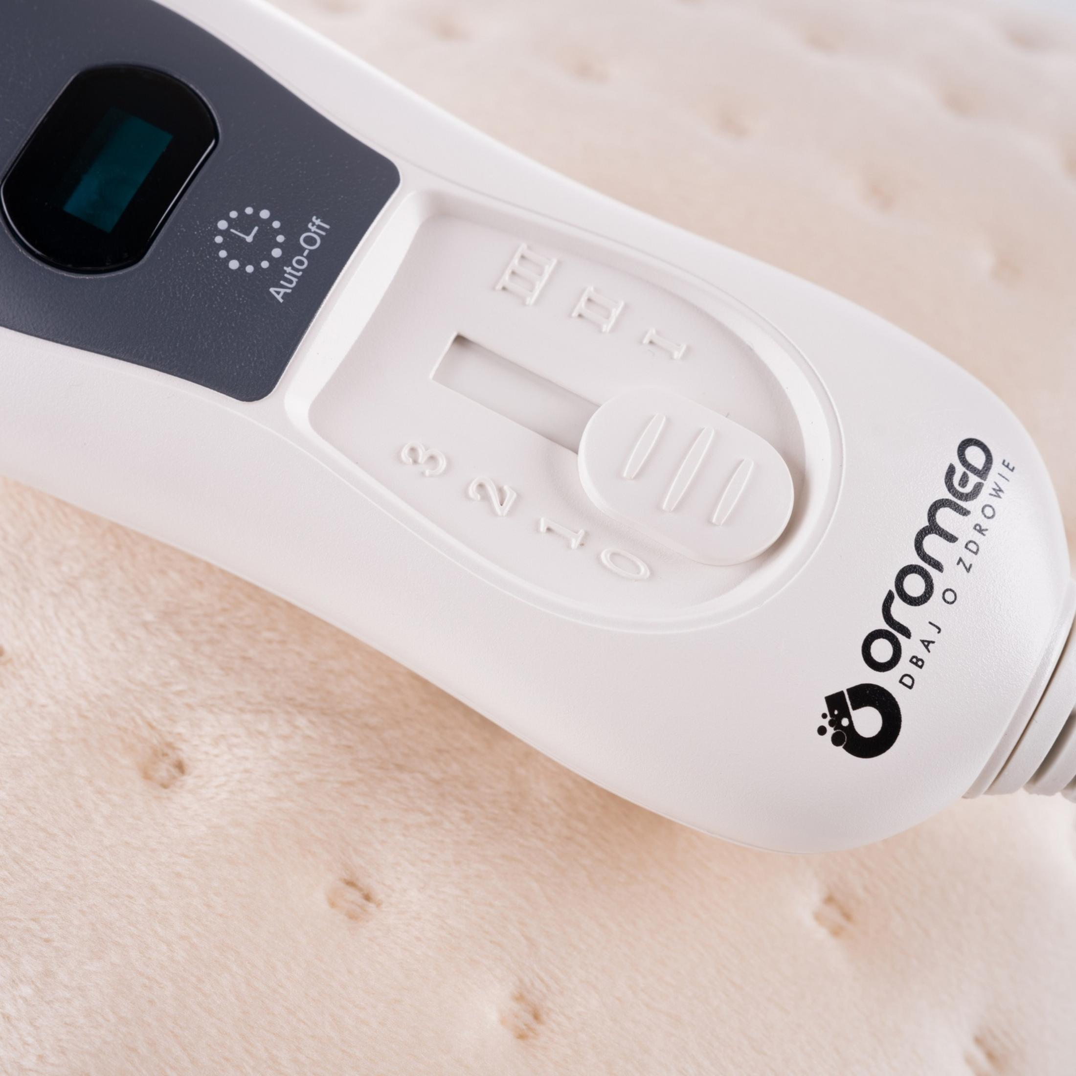 Un controller bianco con spegnimento automatico e impostazioni di temperatura su una coperta morbida.