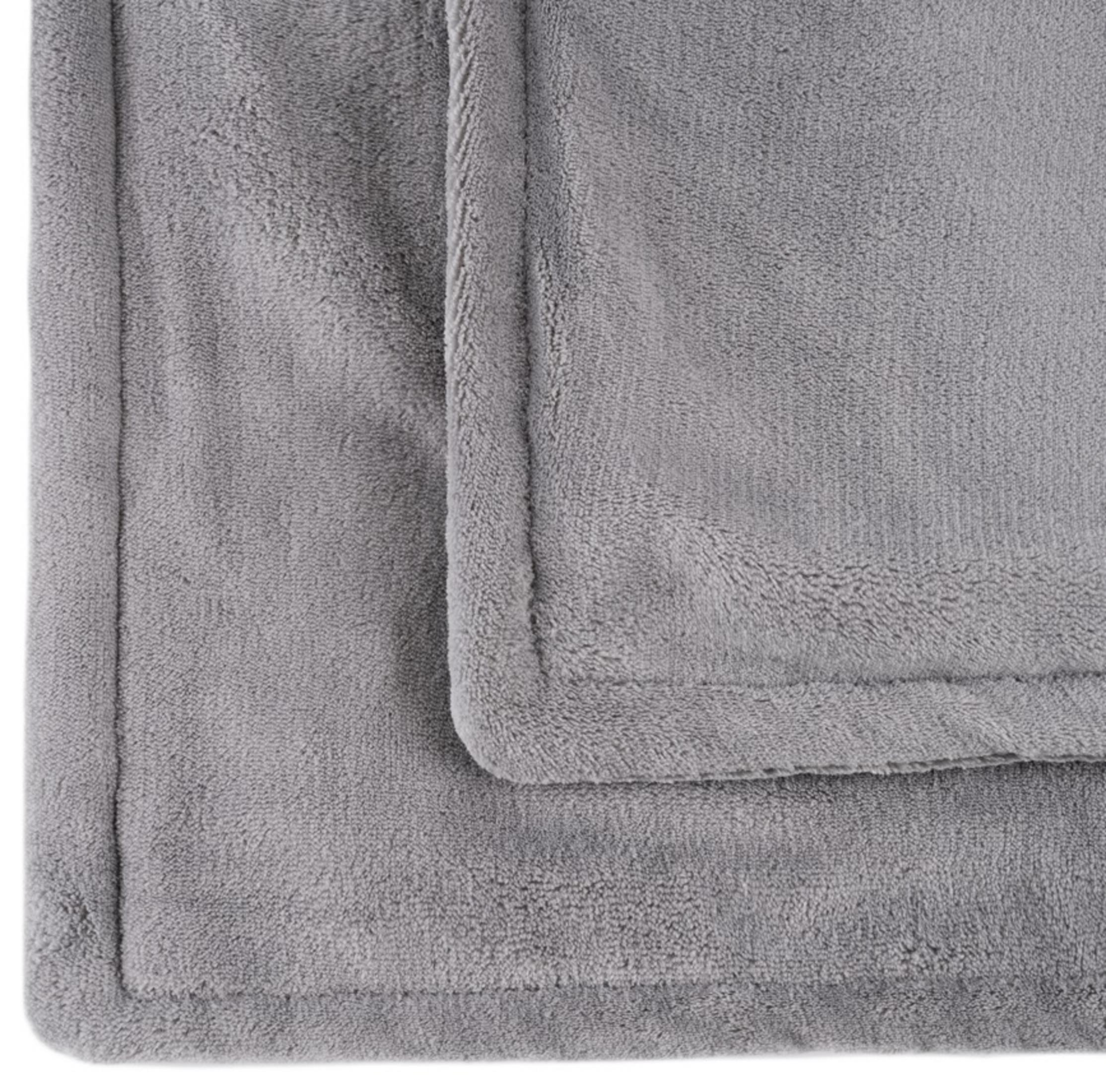 Coperta in pile grigia con texture e orlo visibili.