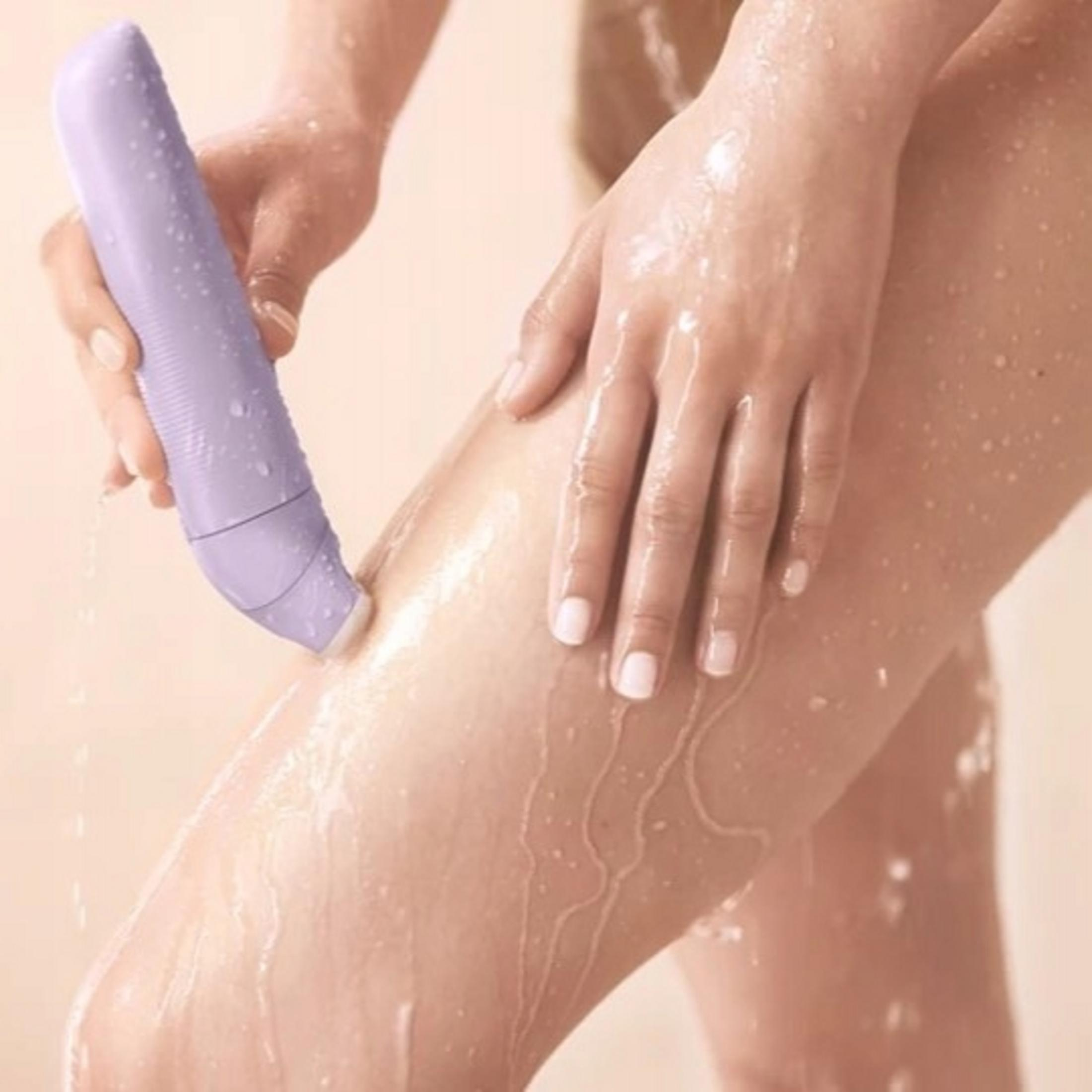 Una mano tiene un dispositivo viola che spruzza acqua su una gamba.