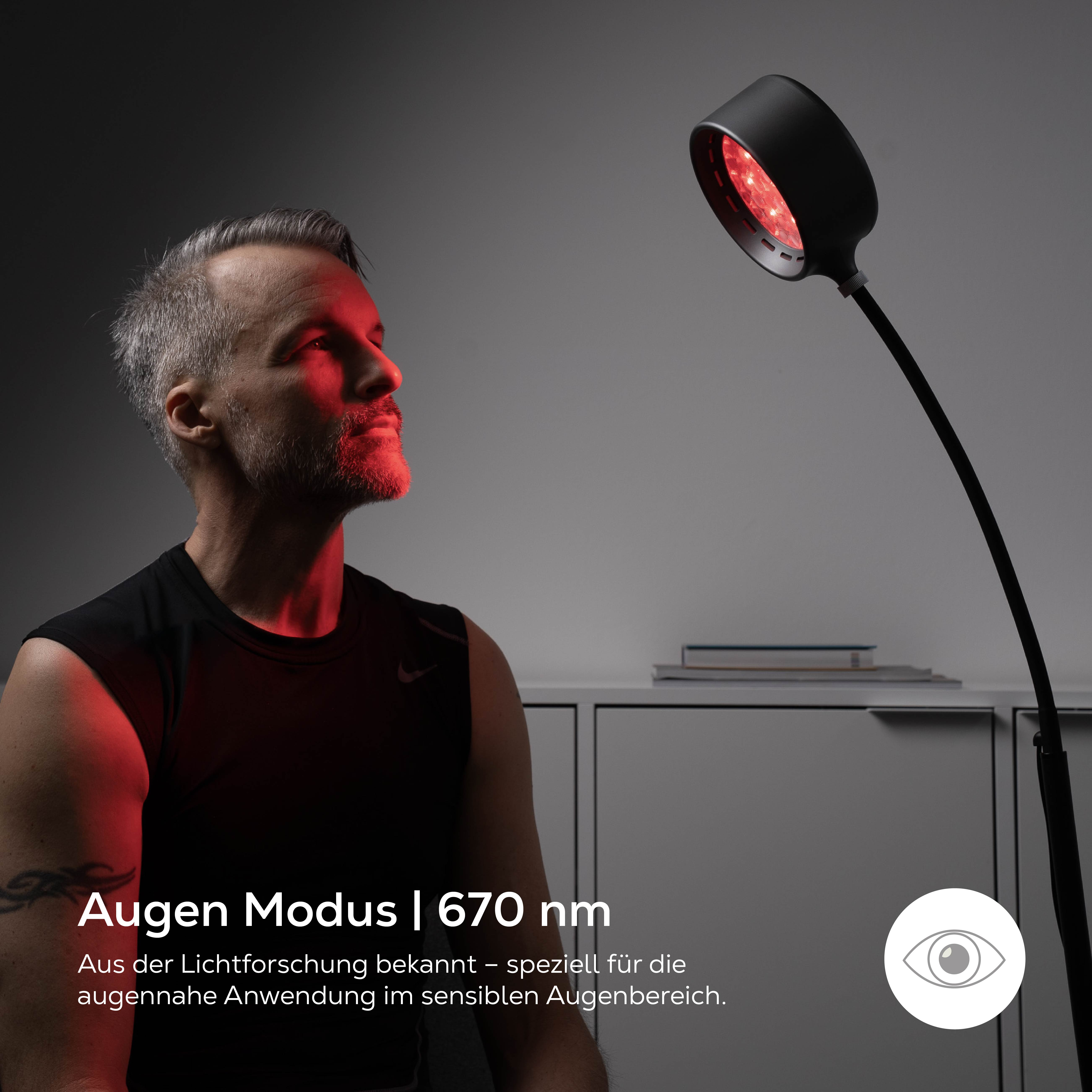 Mann blickt auf Rotlichtlampe, die sein Gesicht anstrahlt. 