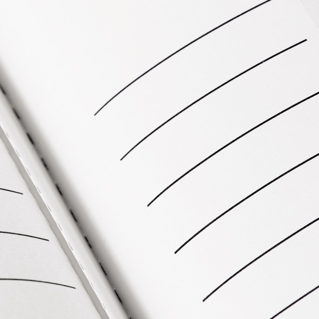Otwarty notatnik z kartkami w linie i czarnymi liniami.