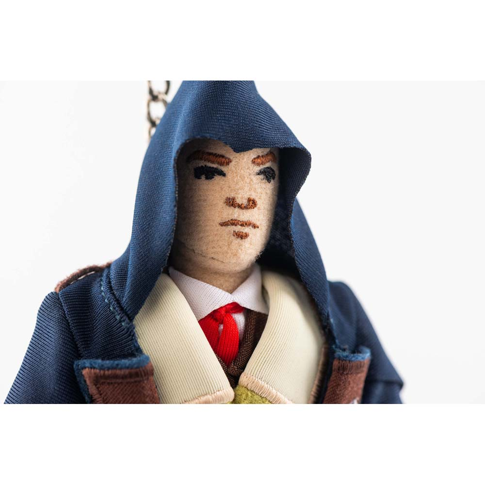 Una bambola di stoffa con cappuccio blu, cravatta rossa e camicia bianca.