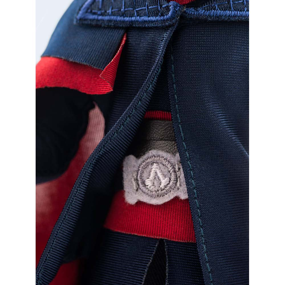 Primo piano di un'uniforme scura con cintura rossa e emblema grigio.