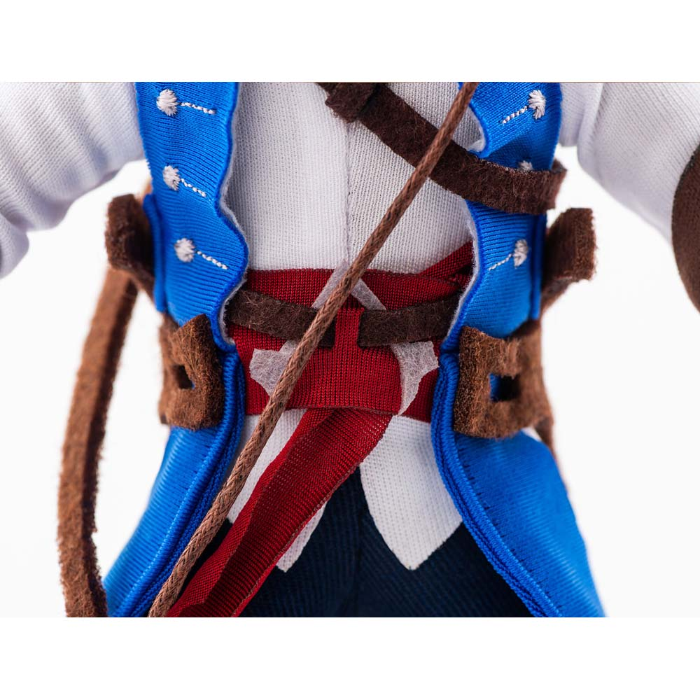 Primo piano di una bambola con gilet blu, fascia rossa e camicia bianca.