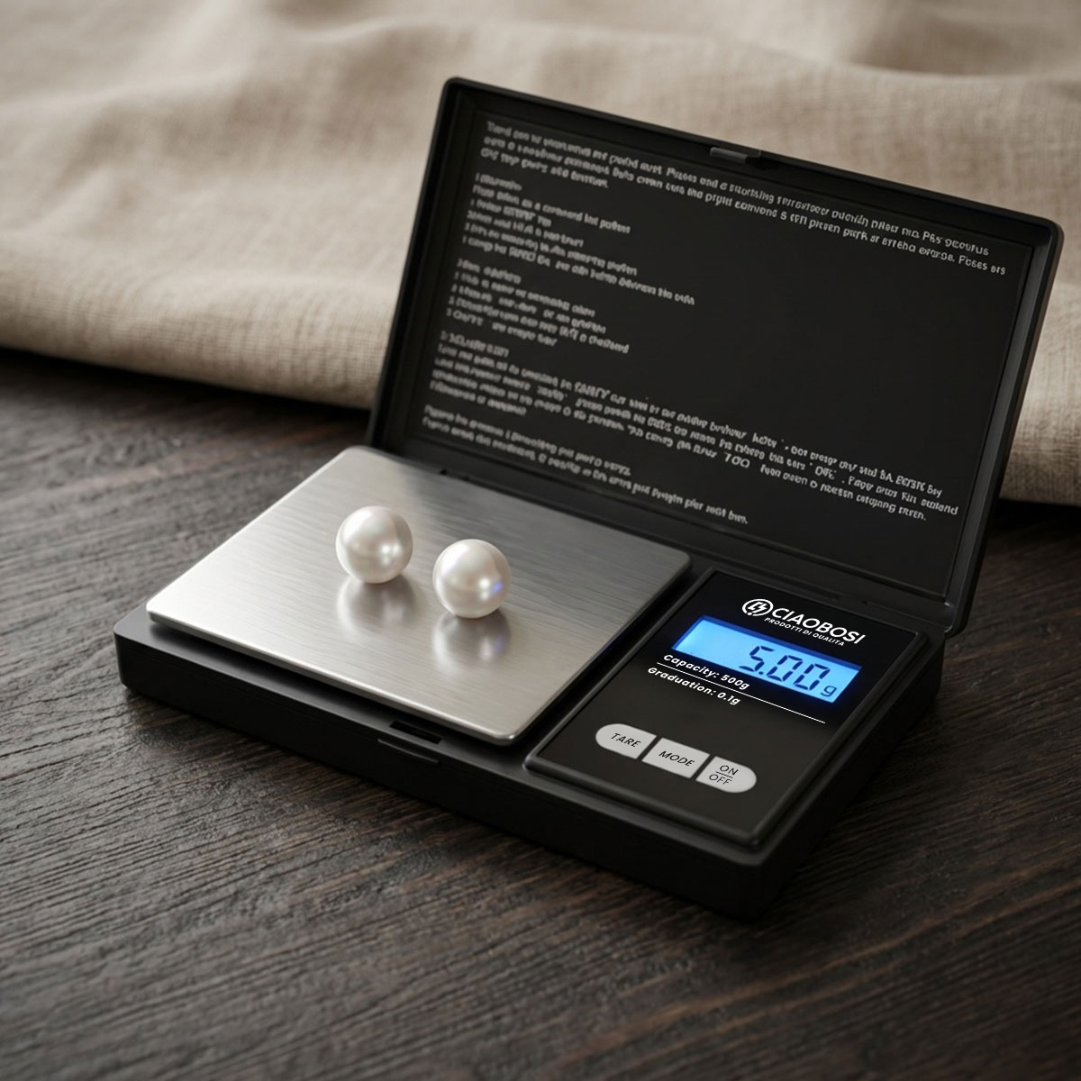 Zwei weiße Perlen liegen auf einer digitalen Waage mit einem Display von 5,00g.