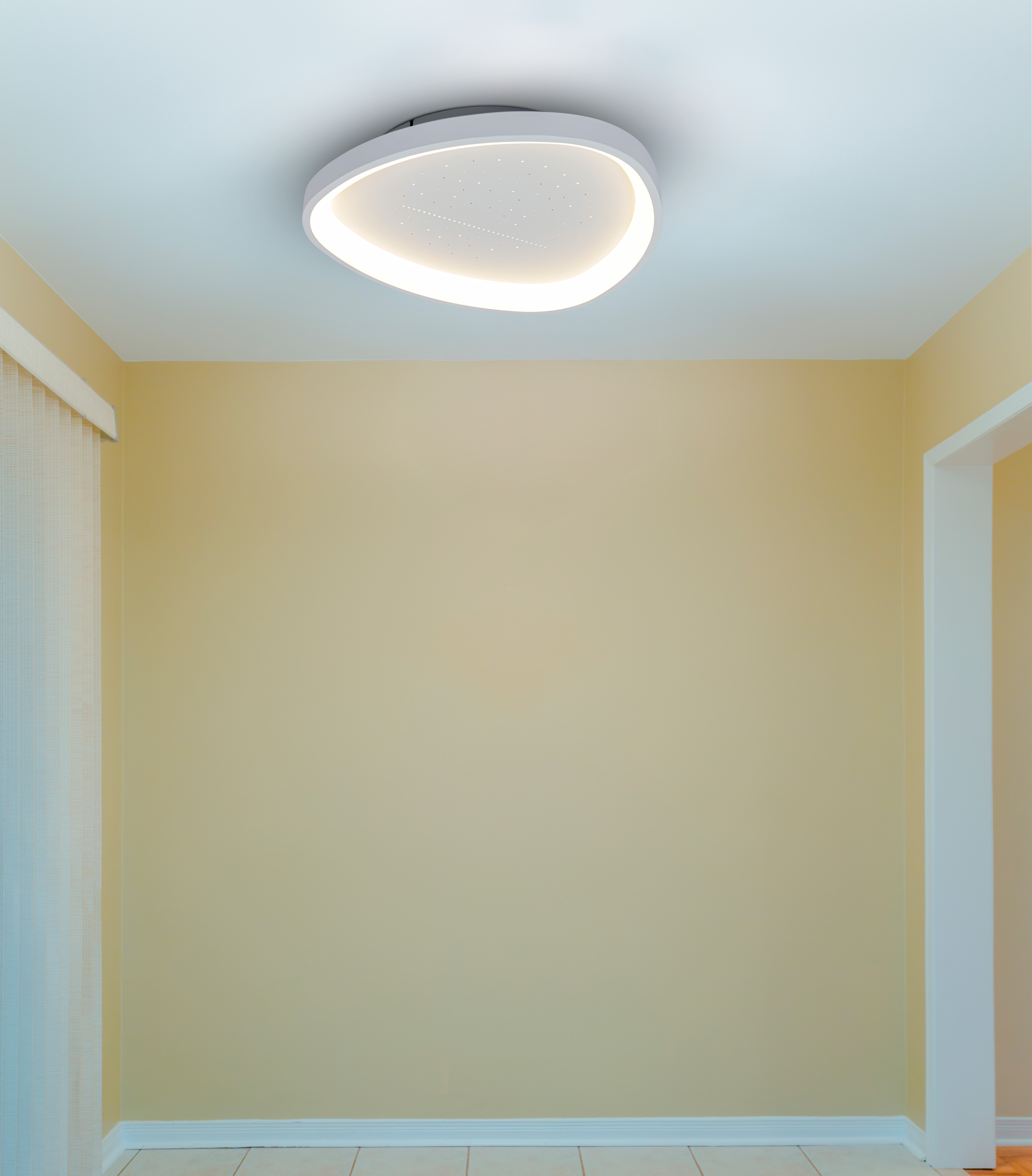 Ein moderner, weißer Deckenventilator mit Licht ist an einer hellgelben Wand montiert.