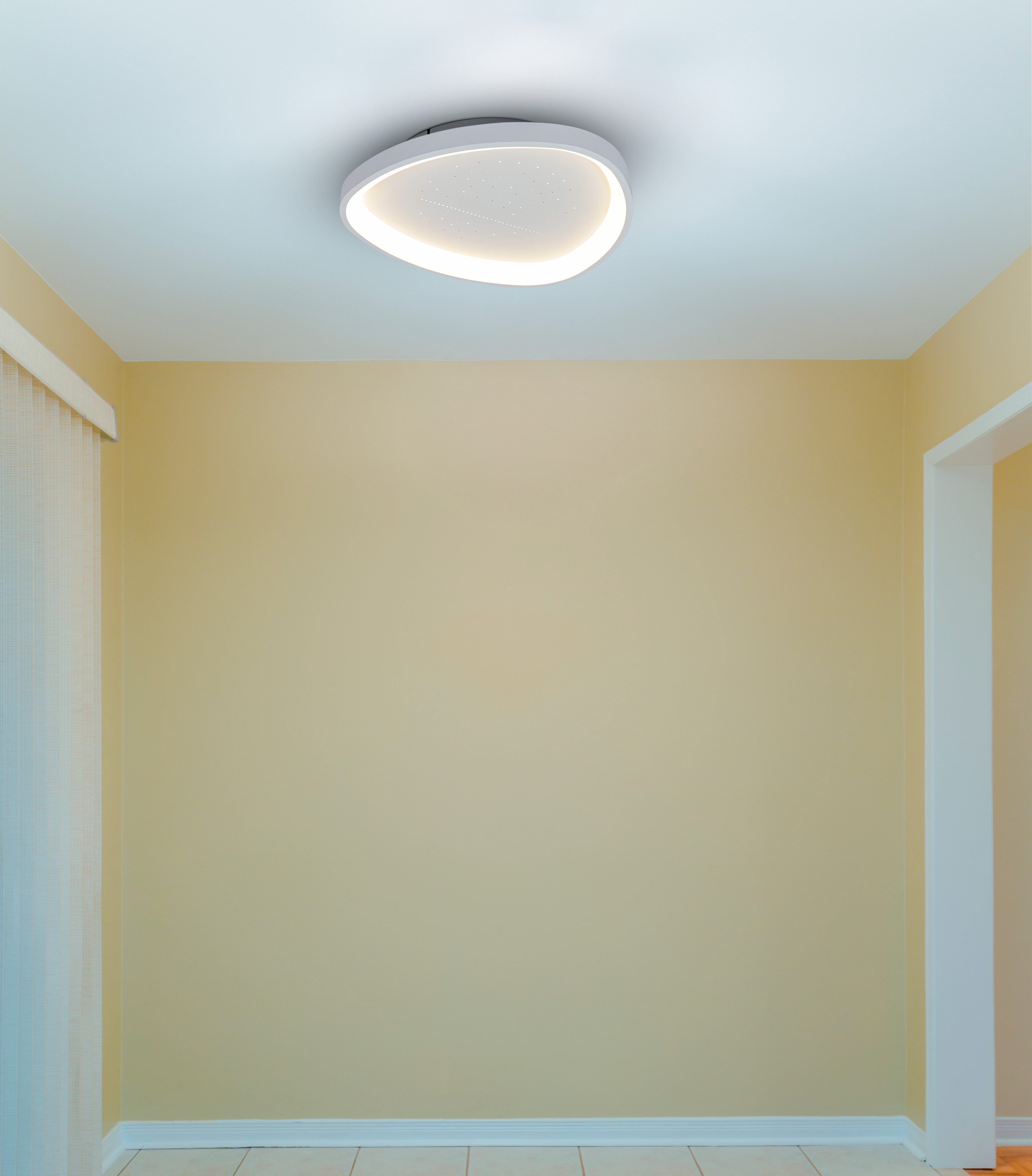 Eine moderne Deckenleuchte mit Sternenmuster leuchtet in einem gelben Raum.
