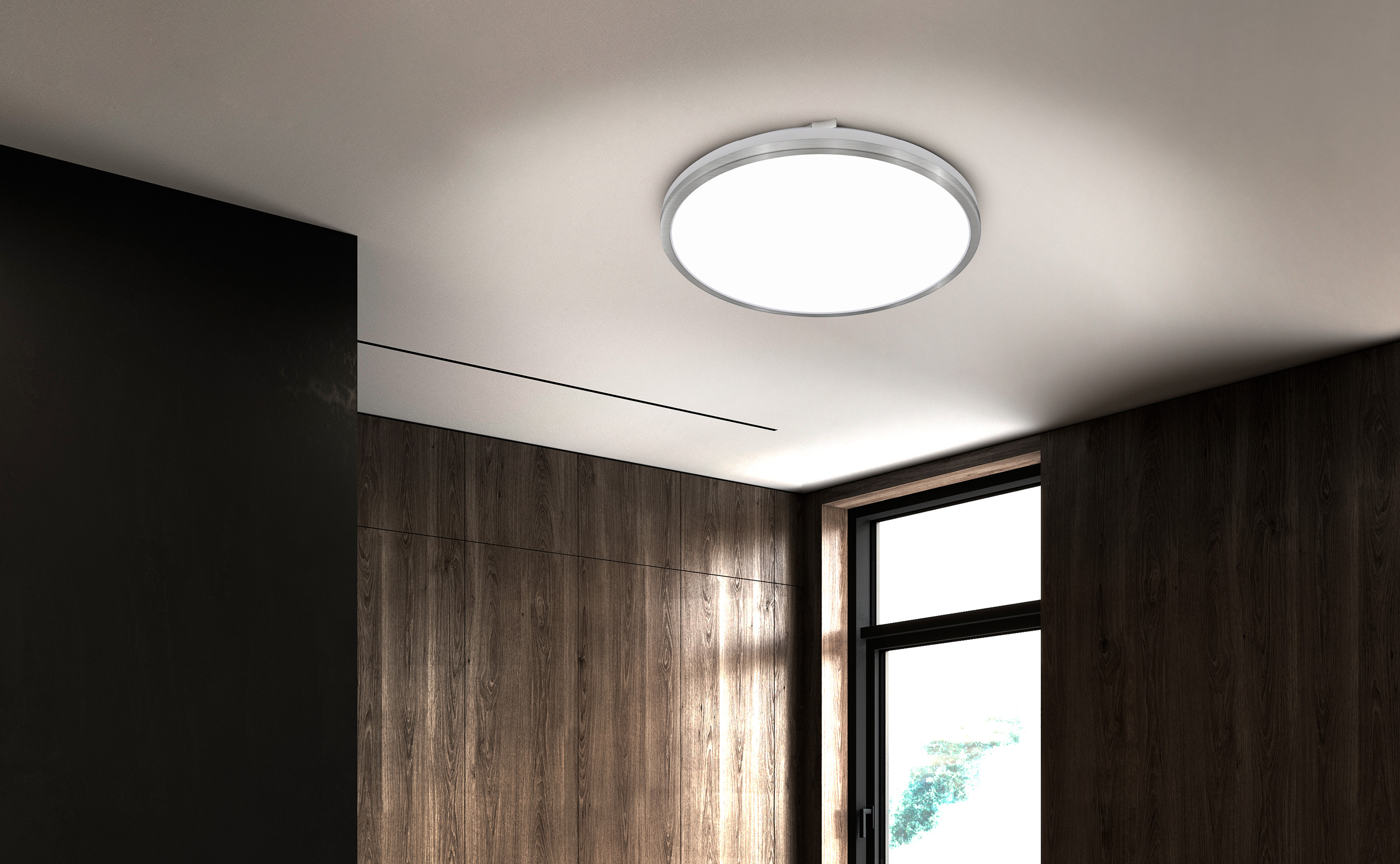 Ein runder Deckenventilator mit silbernem Rand leuchtet auf einer hellen Decke.