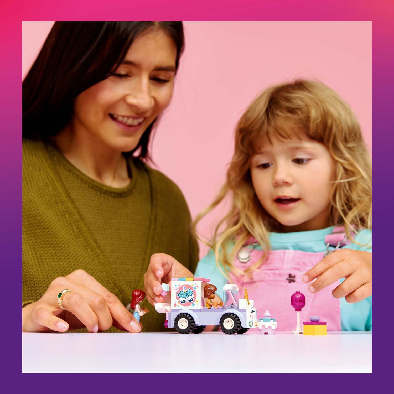 Frau und Kind spielen mit Lego Eiswagen und Figuren auf weißem Tisch.