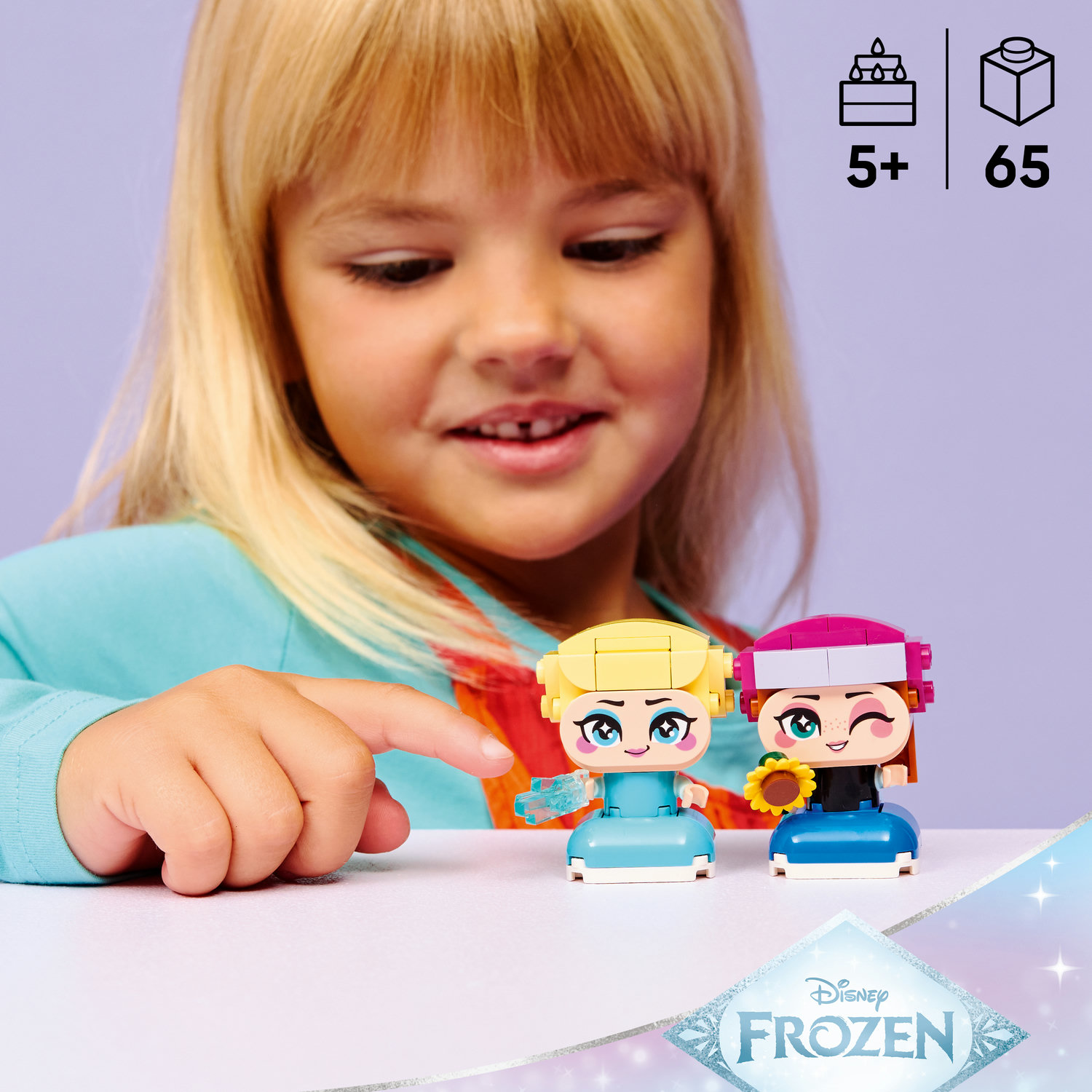 Kız, iki Lego Disney Frozen figürünü işaret ediyor: Elsa ve Anna.