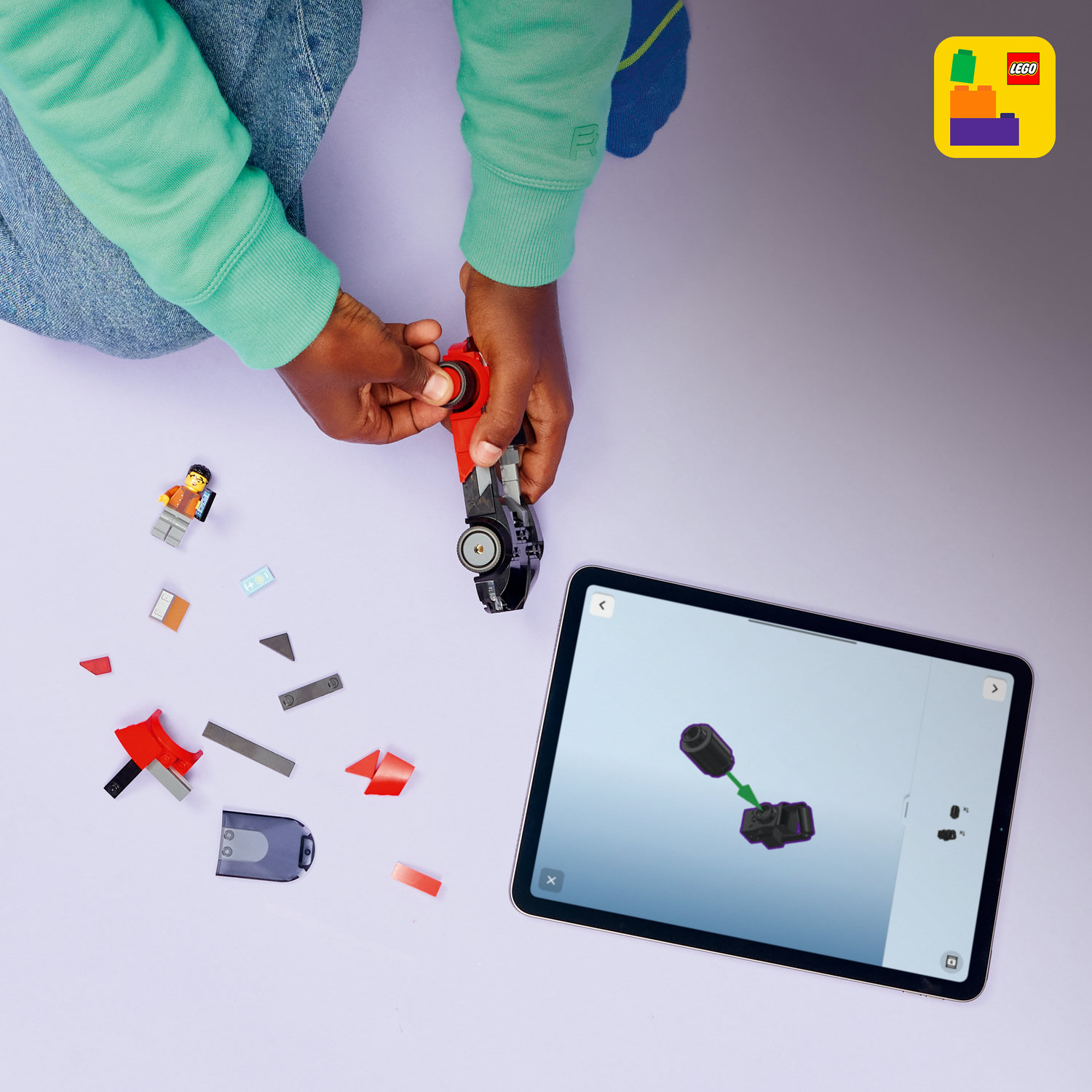 Dziecko buduje samochód z klocków LEGO, instrukcja na tablecie.