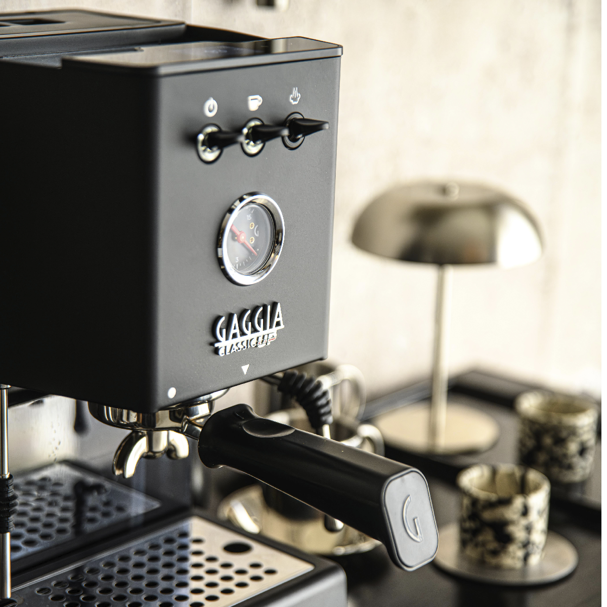 Een zwarte espressomachine met een zilveren meter en handvat.