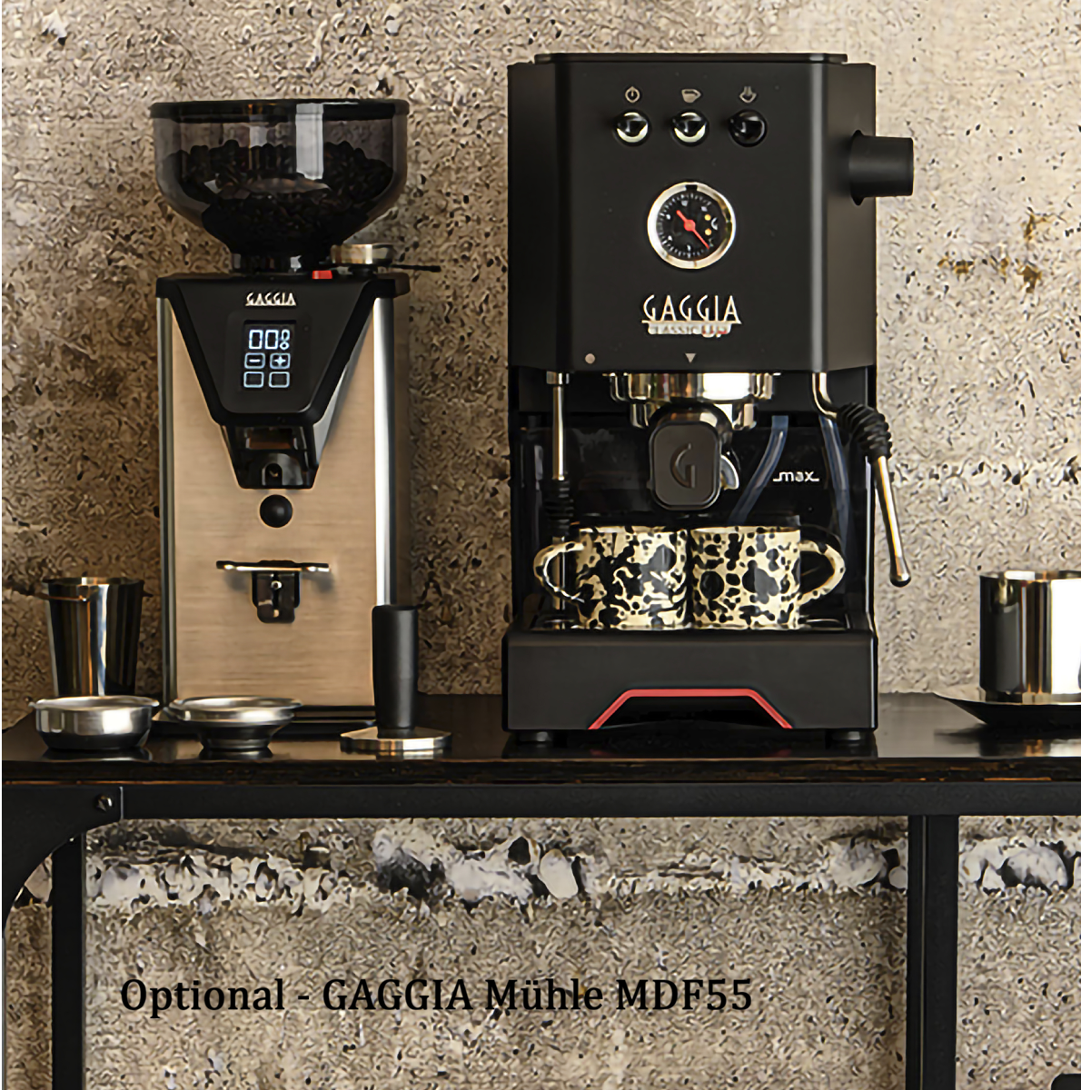 Een zilveren koffiemolen en een zwarte espressomachine met kopjes.