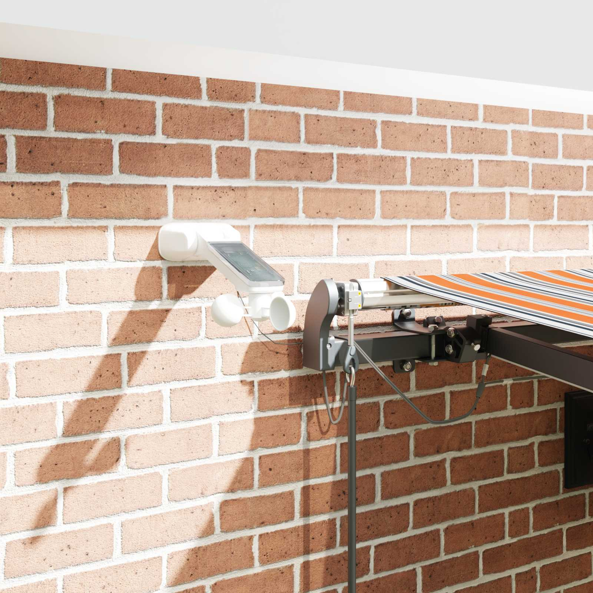 Ein weißer Wetter-Sensor mit Solarpanel und Windmesser an einer Ziegelwand neben einer Markise.