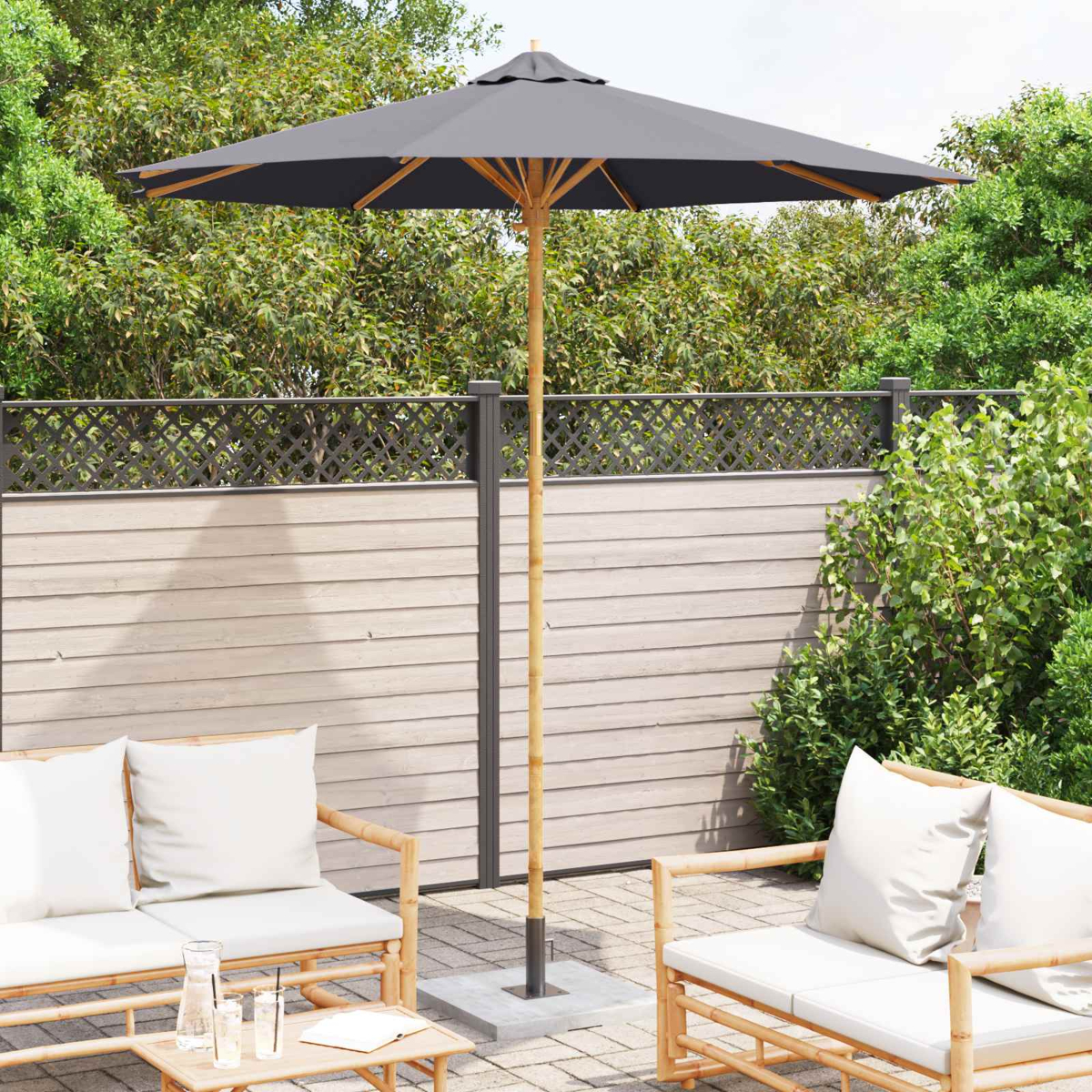 Patio esterno con mobili in bambù, ombrellone grigio e vegetazione lussureggiante.