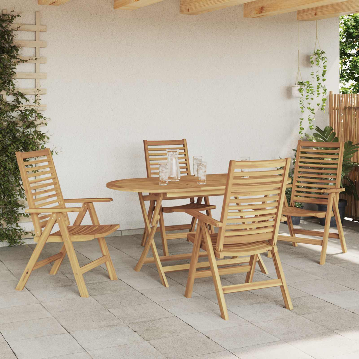 Mesa y sillas de madera en un patio embaldosado con plantas.