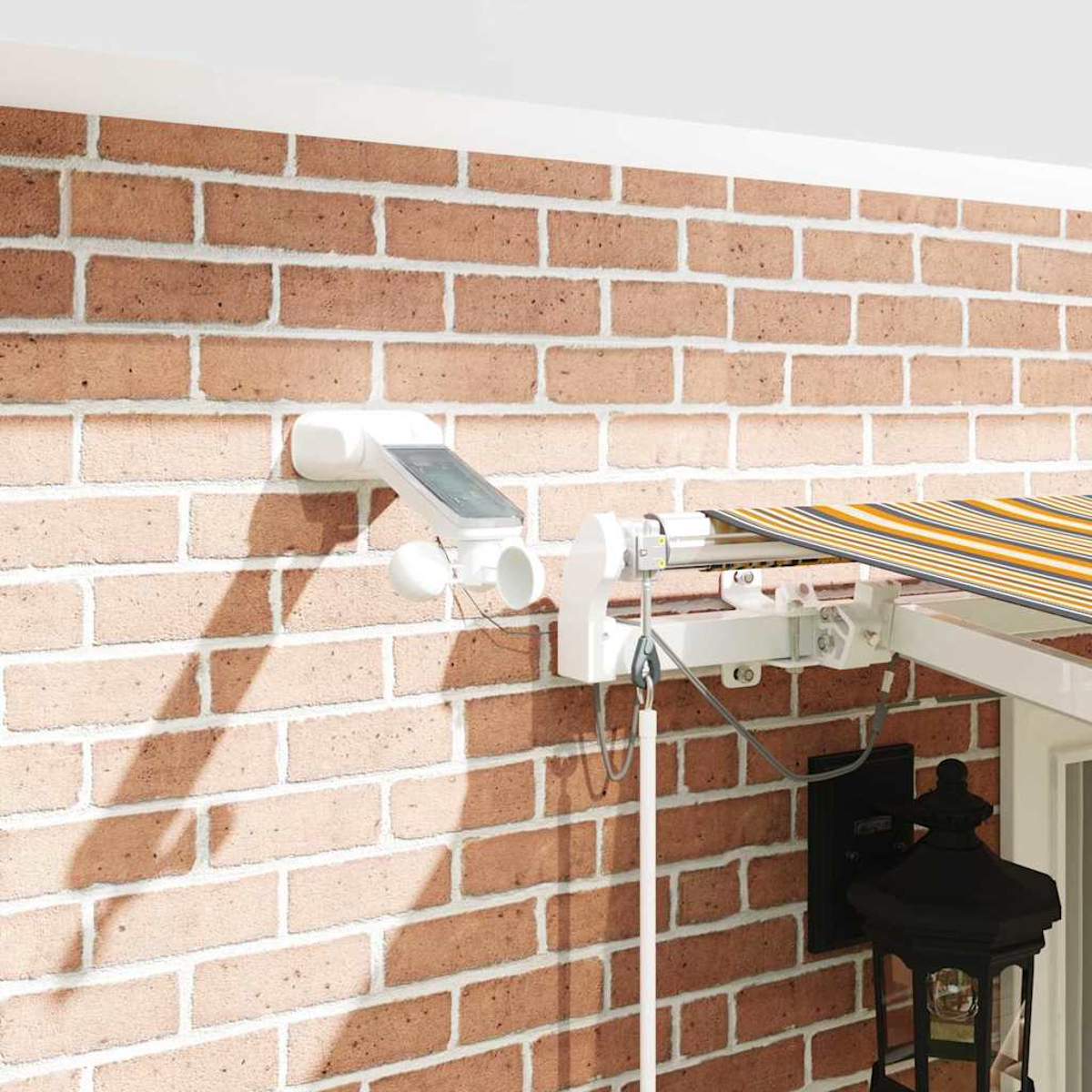 Un marco de toldo blanco con anemómetro solar en una pared de ladrillos.
