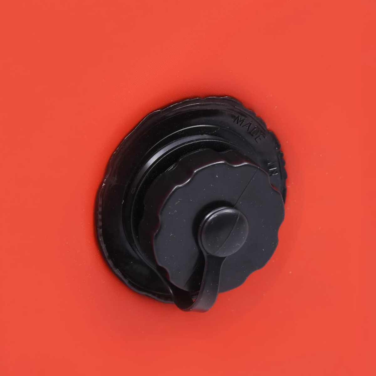 Ein schwarzer aufblasbarer Ventilverschluss auf rotem Stoff.