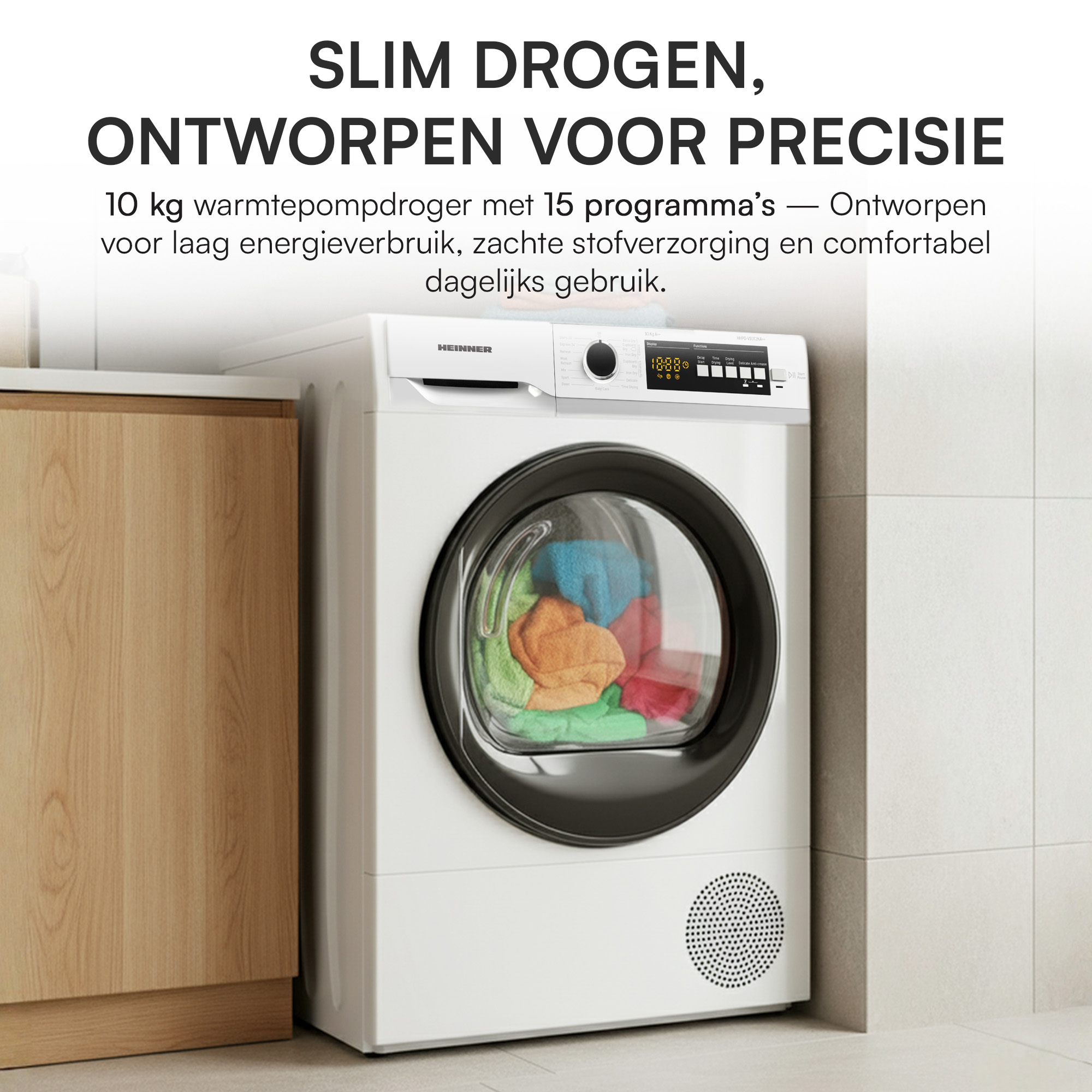 Ein weißer Wäschetrockner mit bunter Wäsche darin. Daneben ein Holzschrank.