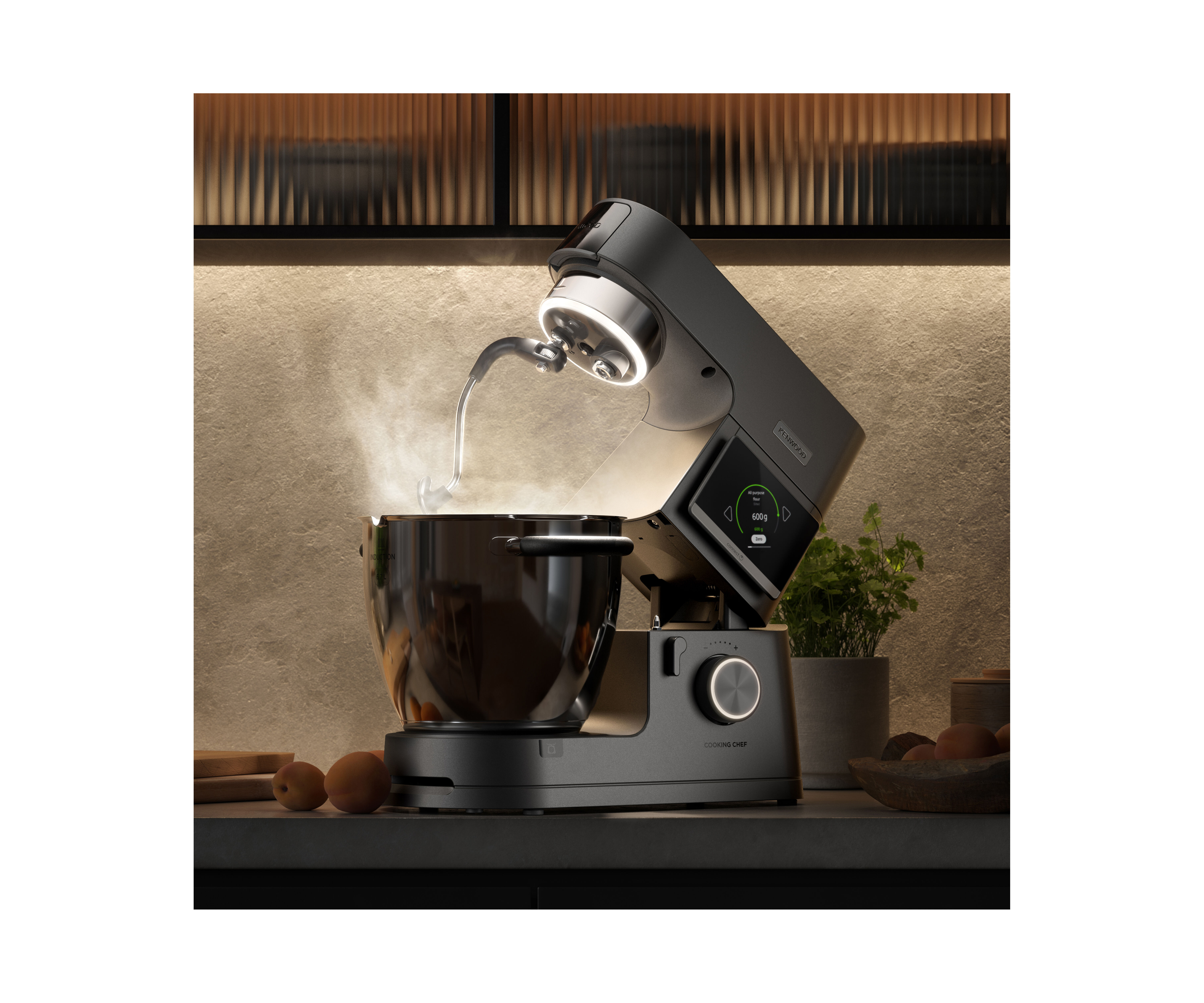 Ein schwarzer Küchenmaschinen-Mixer mit Dampf aus der Schüssel, daneben Obst.