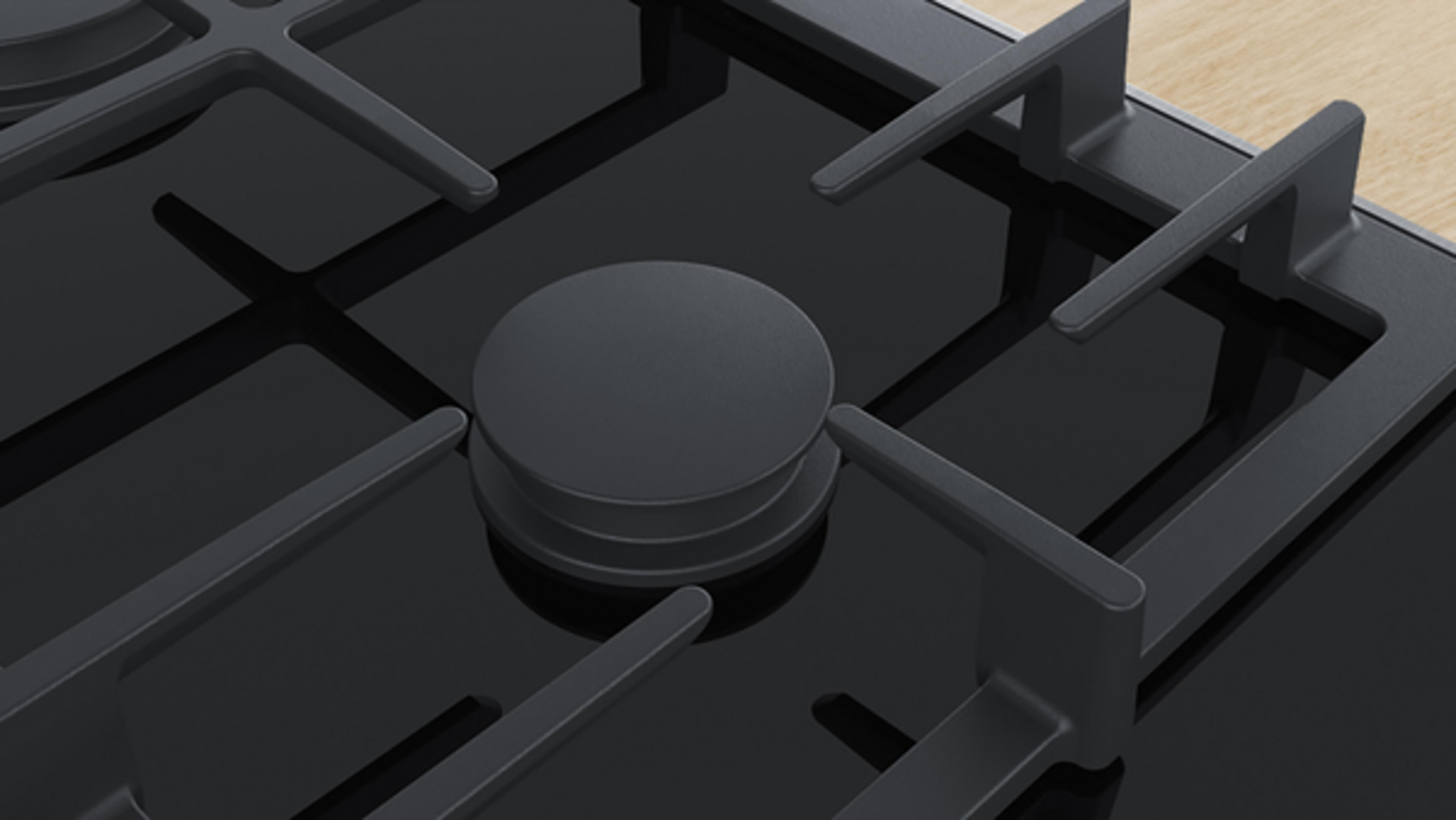 Zbliżenie czarnej płyty gazowej z metalowymi rusztami i okrągłym pokrętłem.