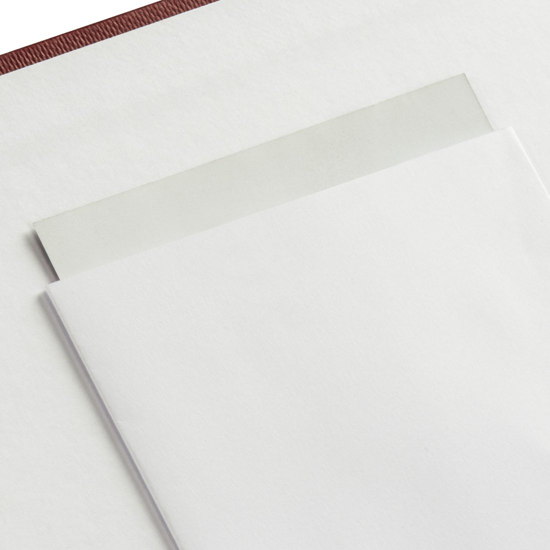 Czerwona okładka z białymi kartkami częściowo zachodzącymi na siebie.