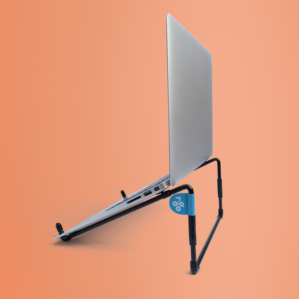 Ein silberner Laptop steht auf einem schwarzen Ständer vor einem orangefarbenen Hintergrund.