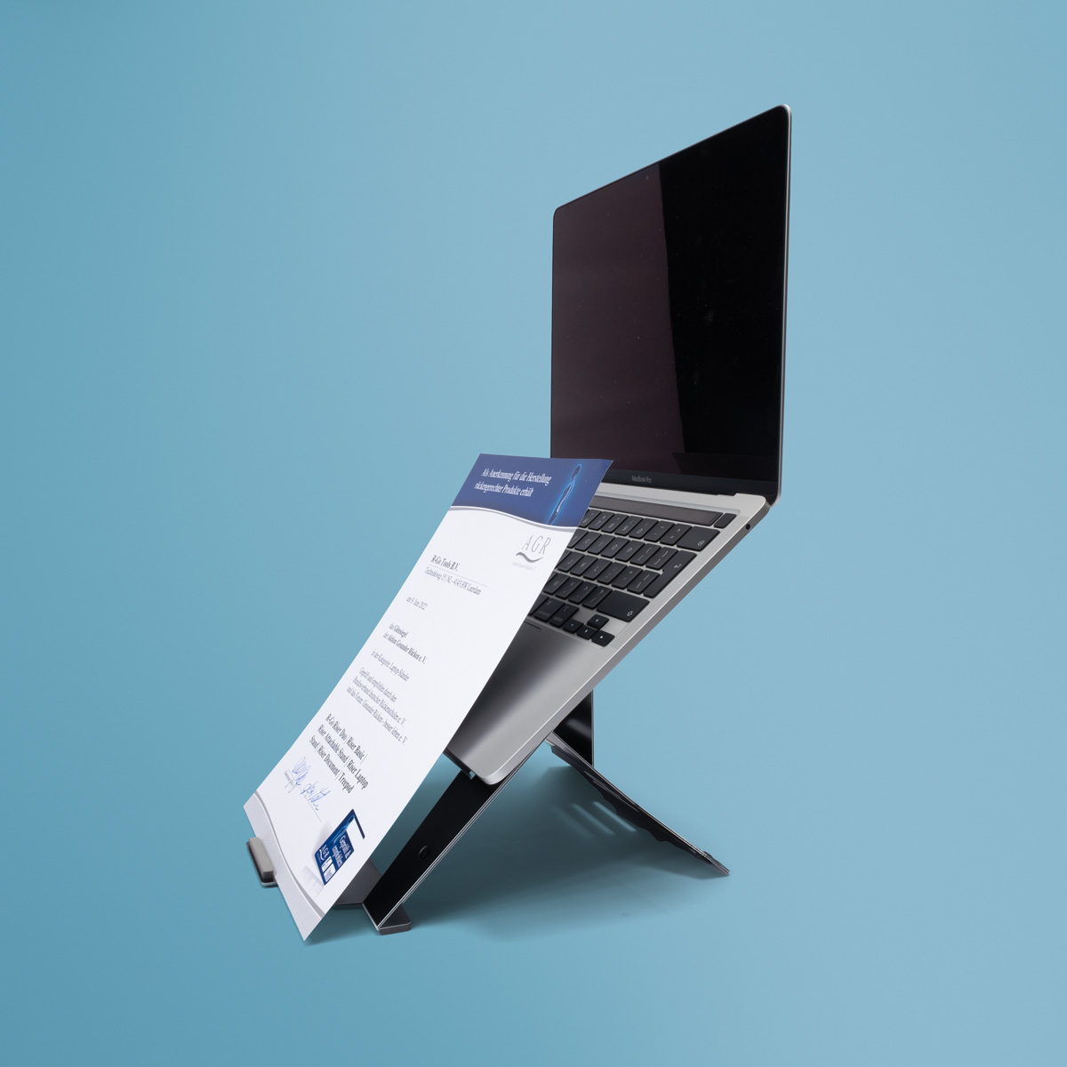 Ein Laptop steht auf einem Ständer, ein Dokument ist davor befestigt.