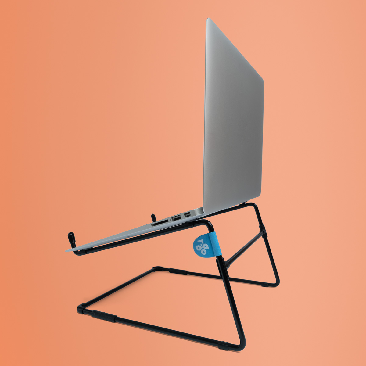 Ein silberner Laptop steht auf einem schwarzen Ständer vor einem orangefarbenen Hintergrund.