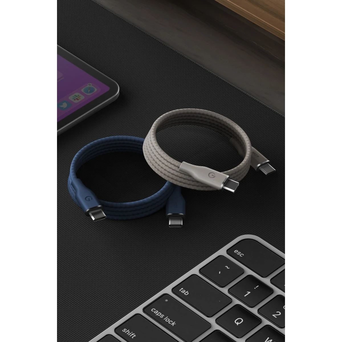 Mavi ve gri renkli iki USB-C kablosu tablet yanında klavyede duruyor.
