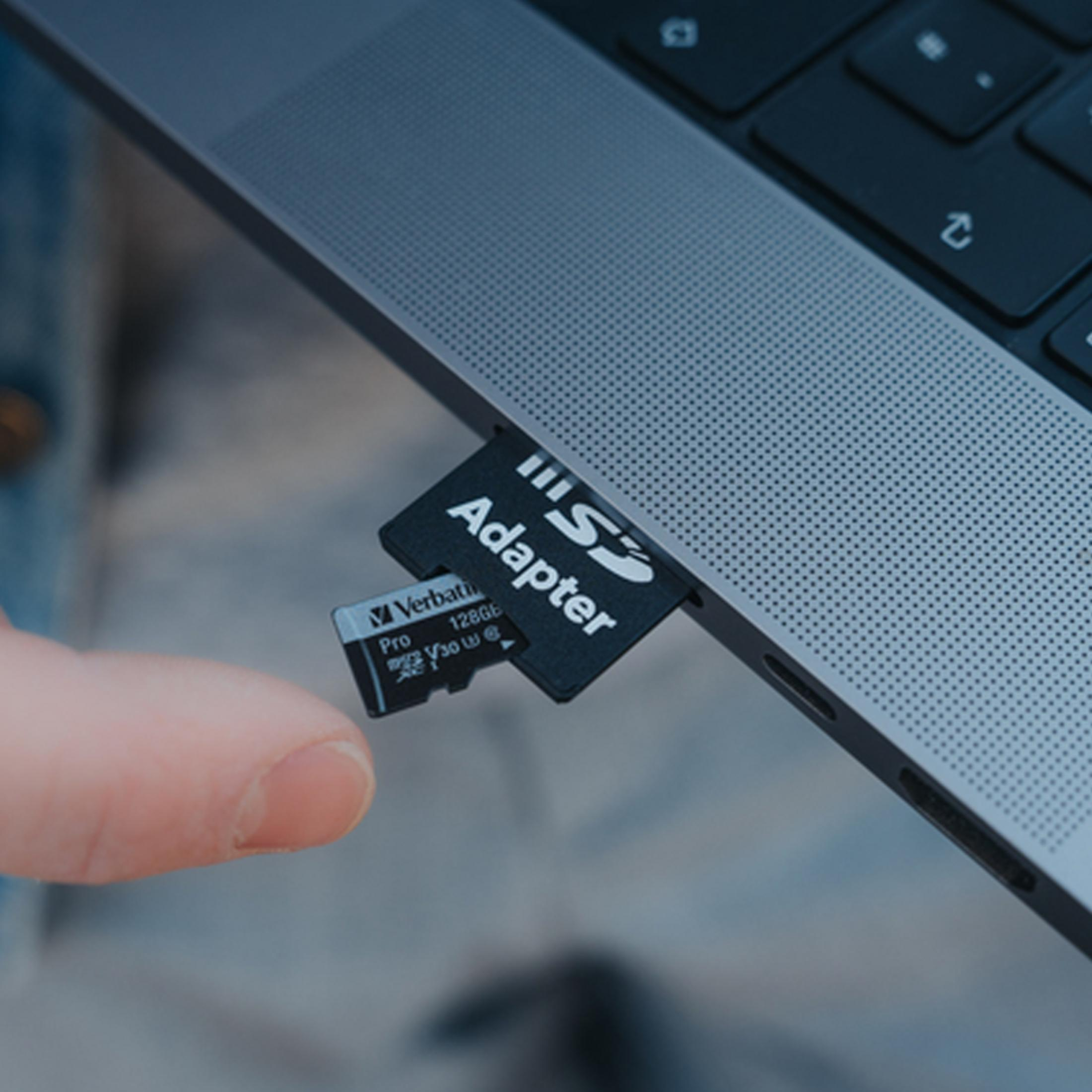 Dłoń wkłada kartę SD do gniazda adaptera laptopa.