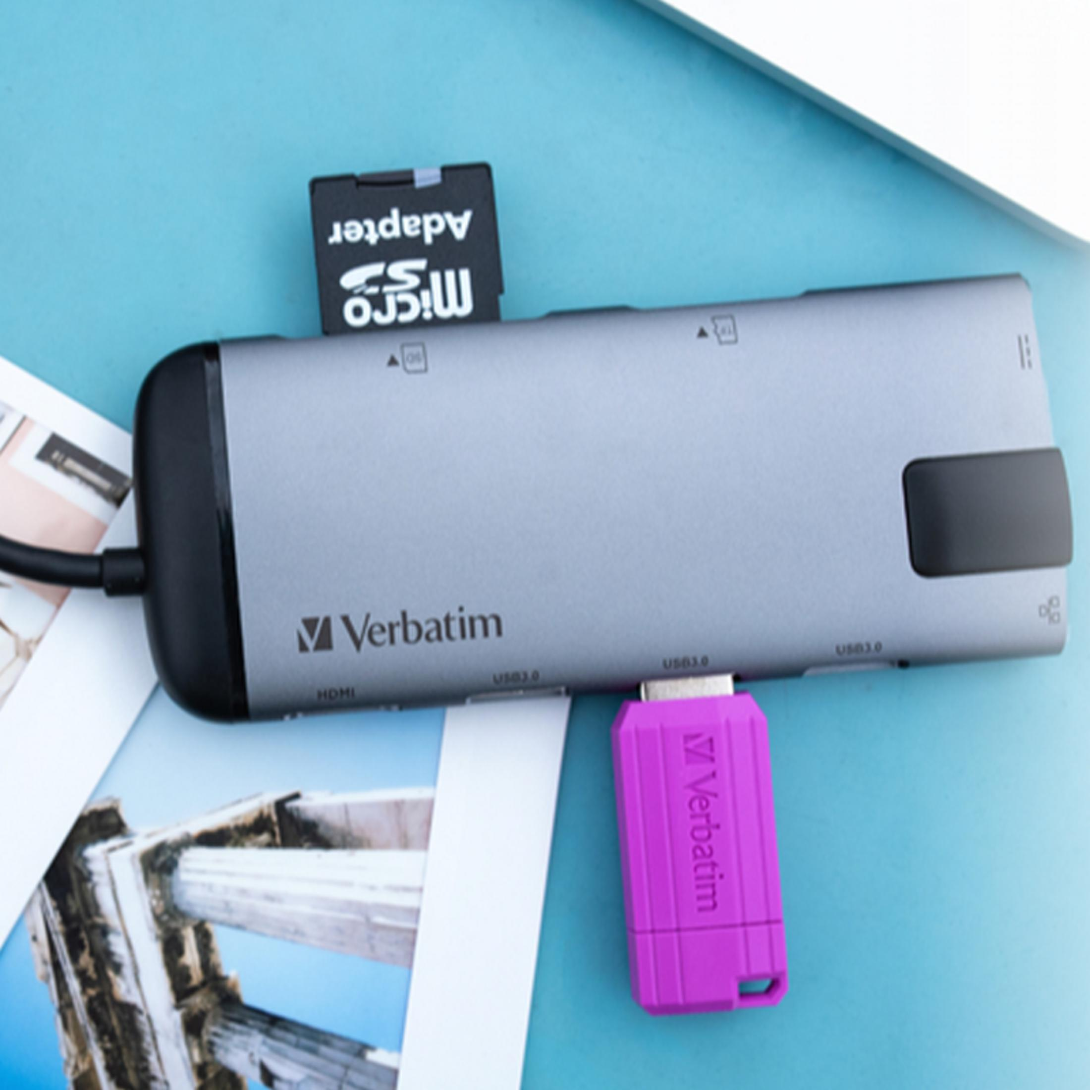 Szara stacja dokująca USB-C z kartą SD i różowym pendrivem na niebieskim tle.