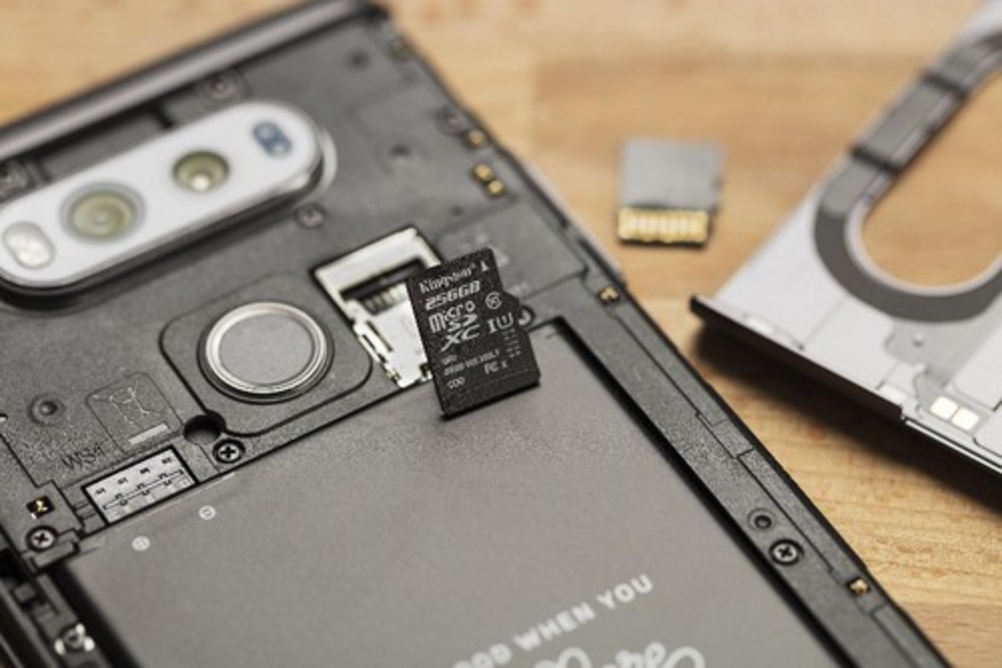 Una scheda di memoria Kingston 256GB MicroSD XC I U accanto alla batteria di uno smartphone.