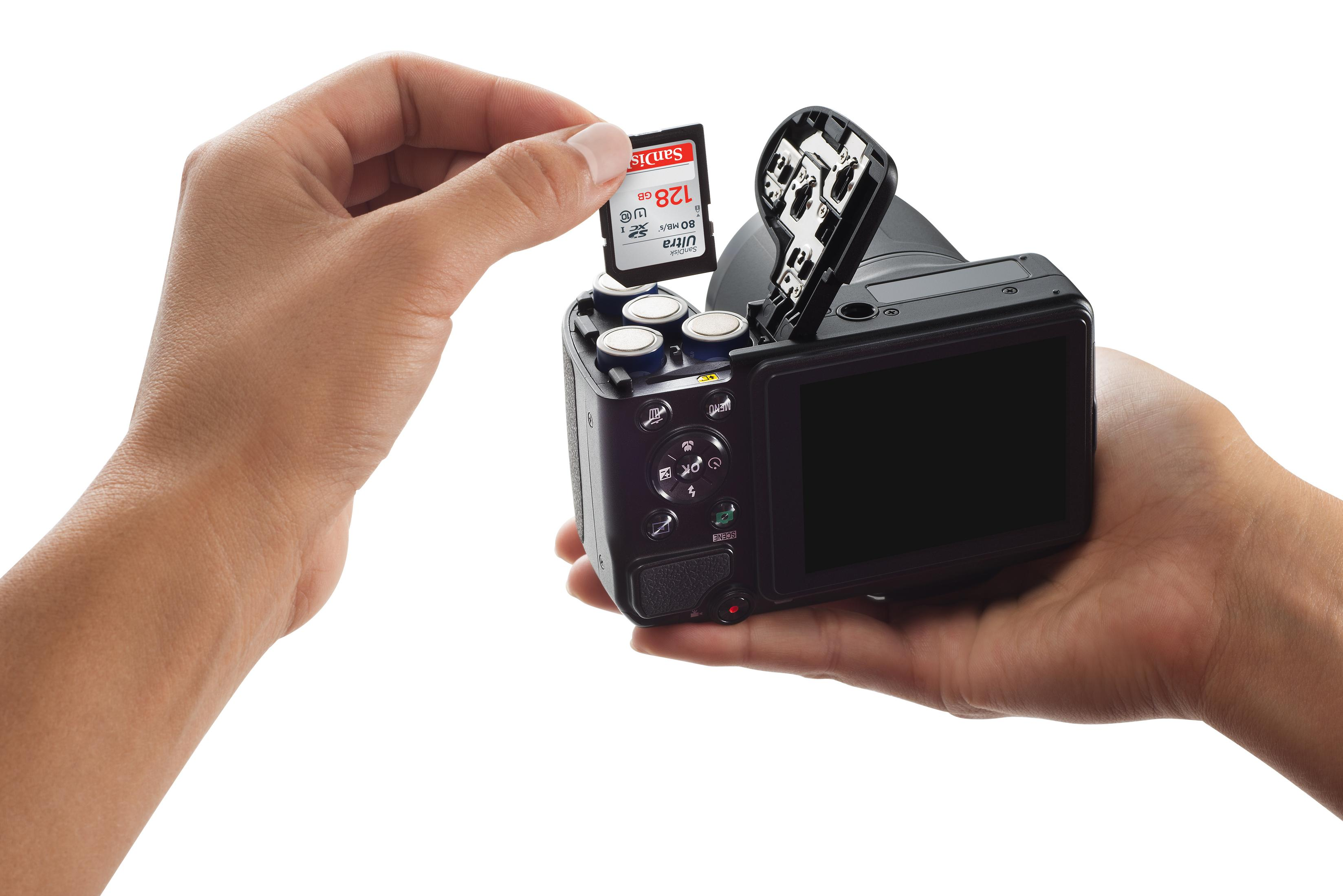 Dłoń wkłada kartę SD 128 GB do aparatu z otwartą komorą.
