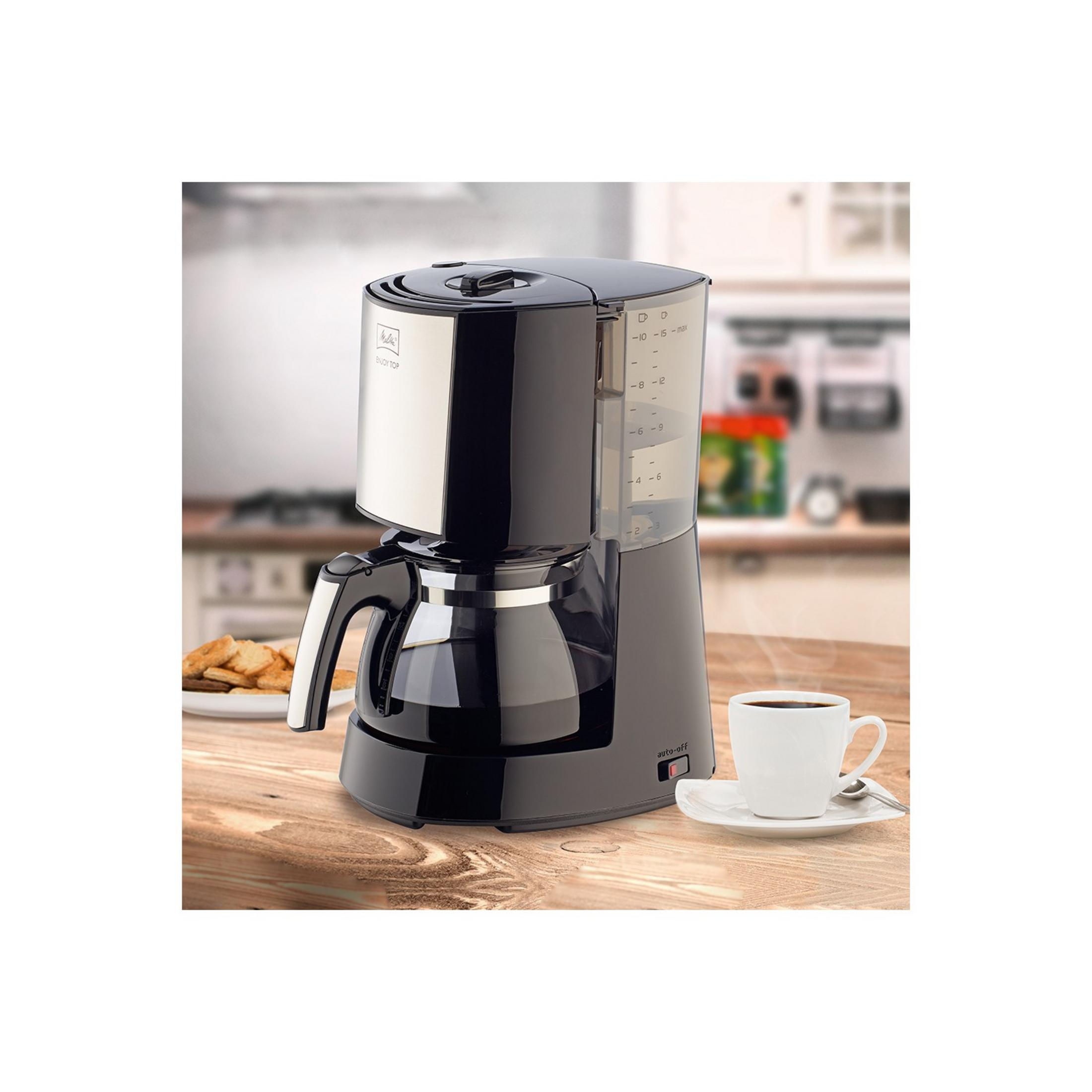 Czarny ekspres do kawy ze szklanym dzbankiem, filiżanka kawy, ciasteczka na drewnianym stole.