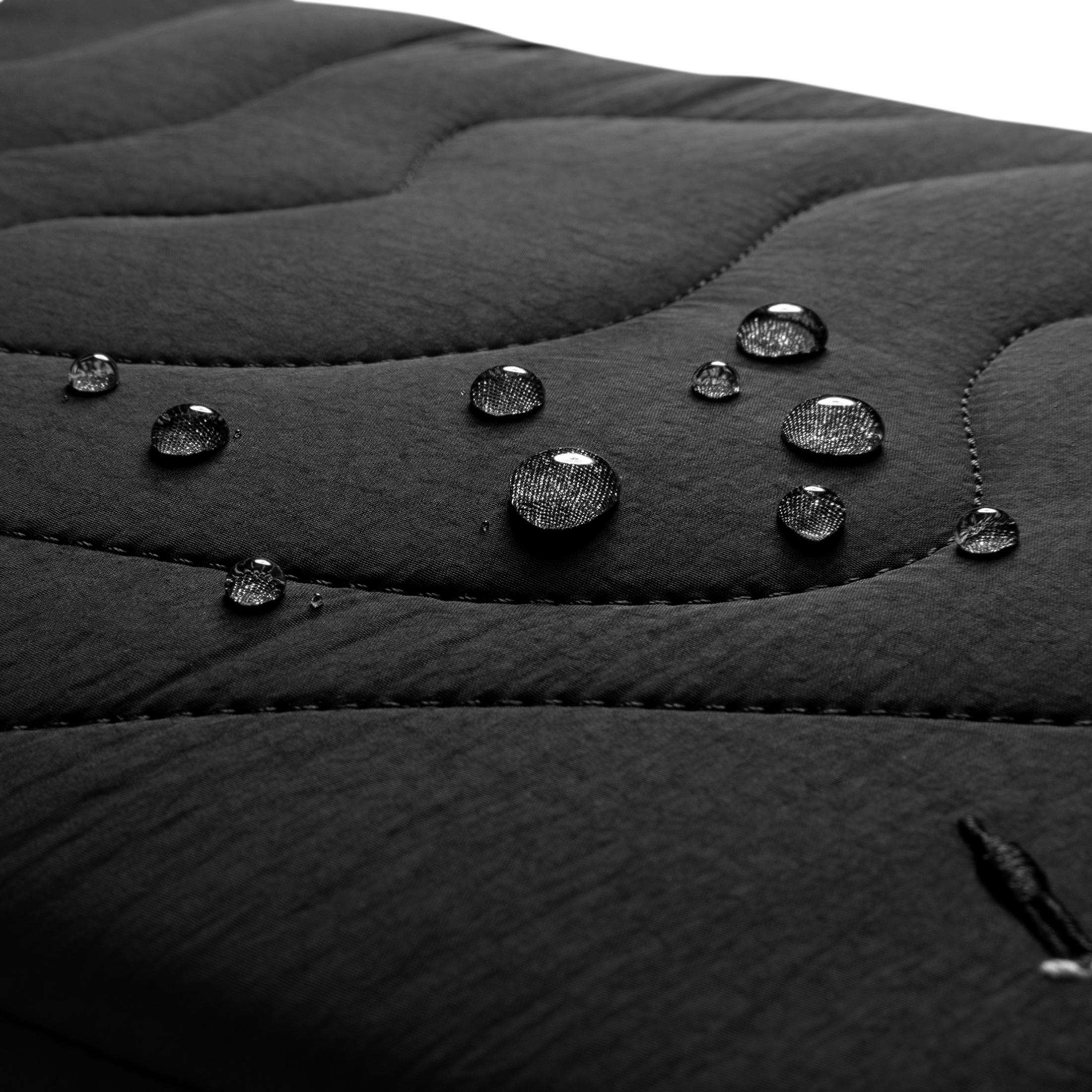 Krople wody na czarnej pikowanej tkaninie, zbliżenie.