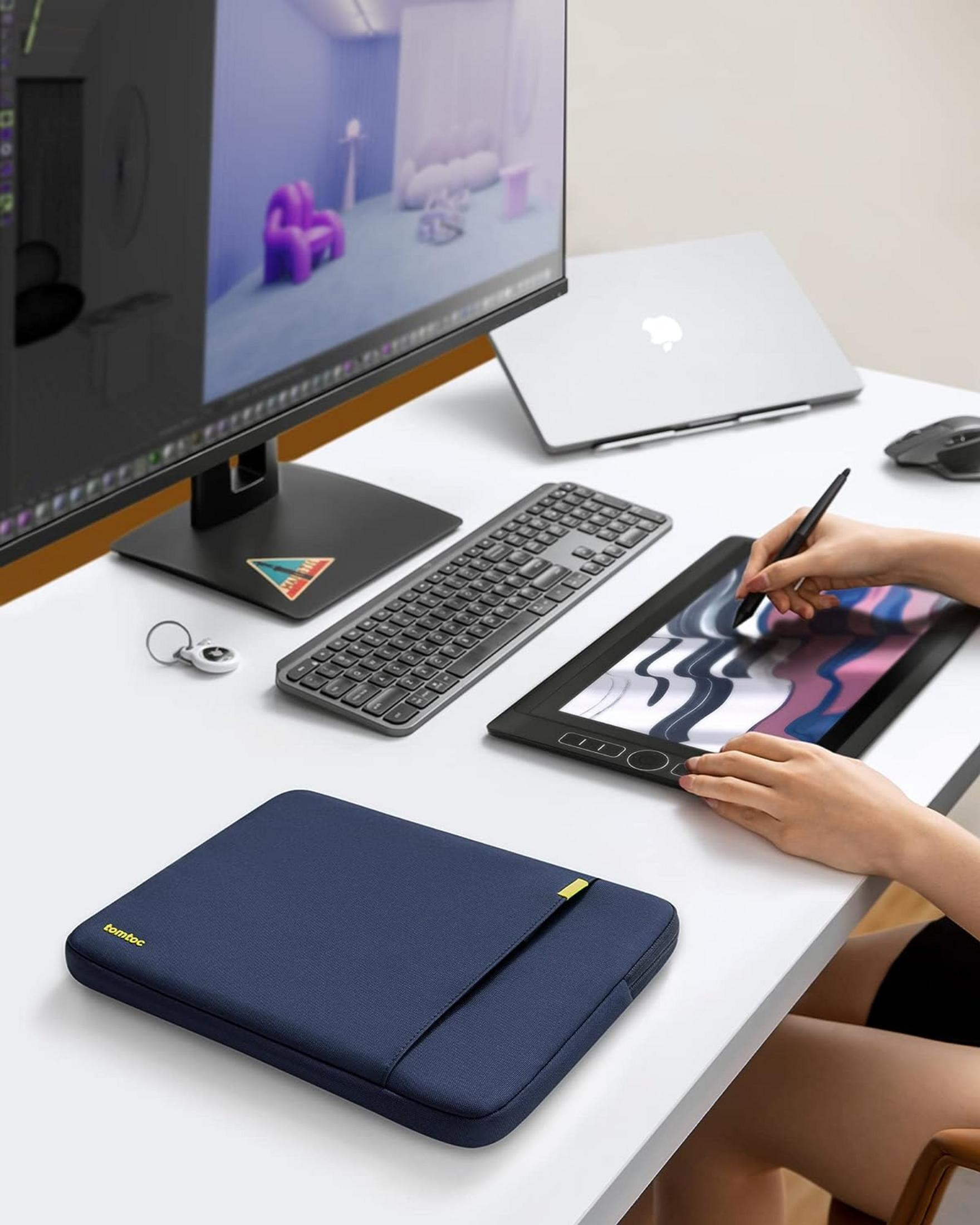 Biurko z monitorem, klawiaturą, myszką, laptopem i tabletem graficznym.