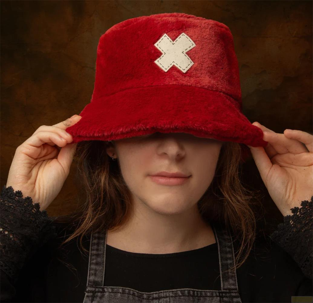 Eine junge Frau mit einem roten Eimerhut mit einem weißen Kreuz trägt Latzhosen.