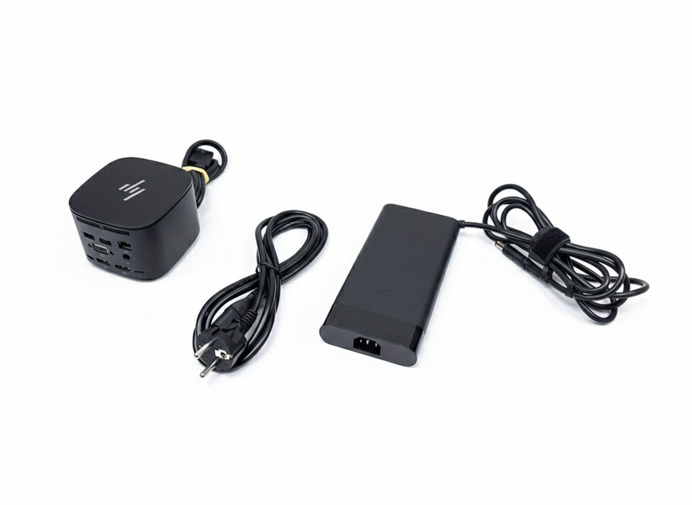 Schwarzer Mini-PC, Netzteil und Kabel auf weißem Hintergrund.