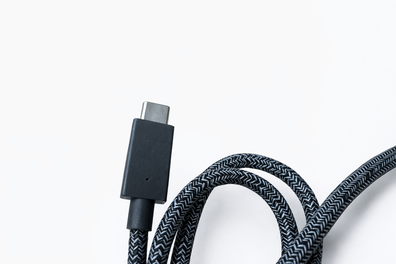 Ein schwarzes USB-C-Kabel mit grauem Zickzackmuster liegt auf weißem Grund.