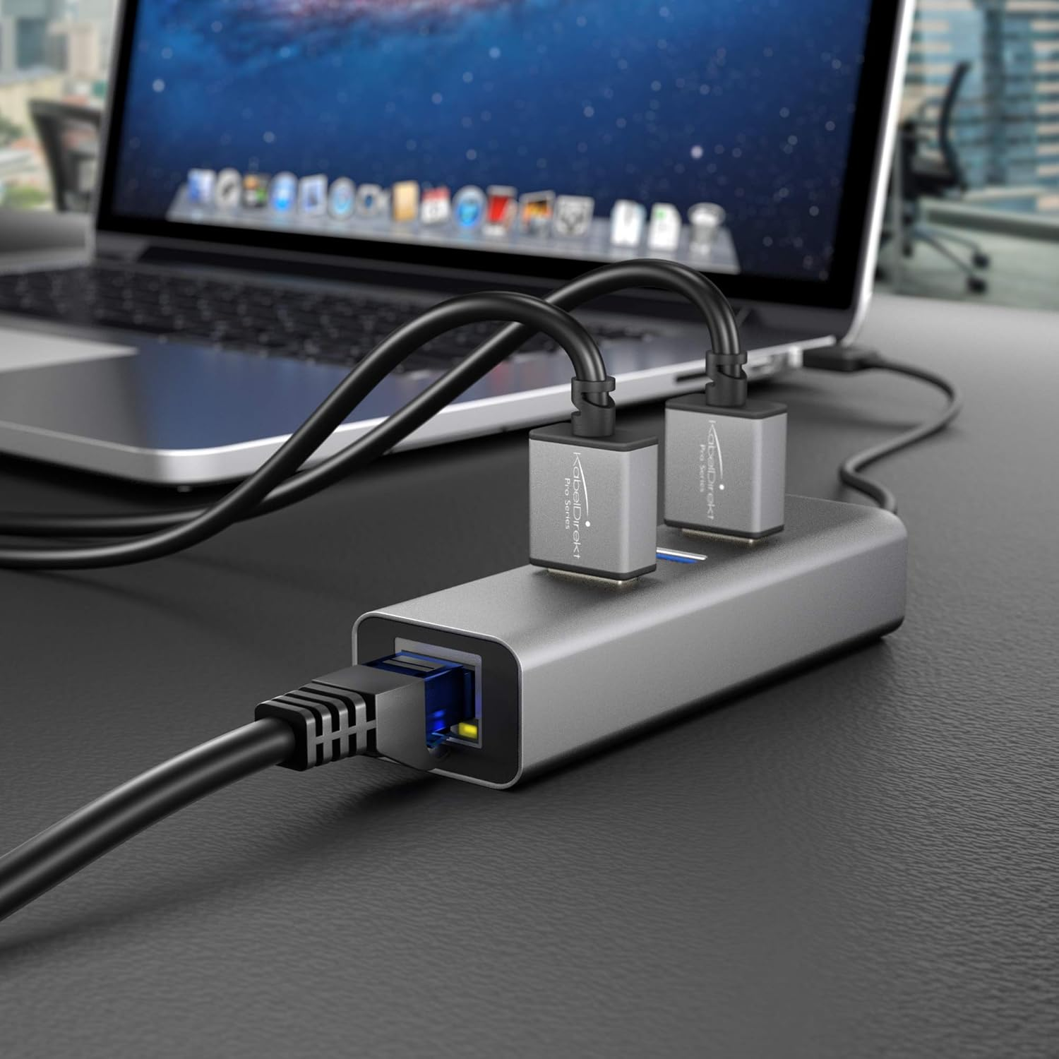 Laptop z szarym hubem USB-C podłączonym do kabli sieciowych.