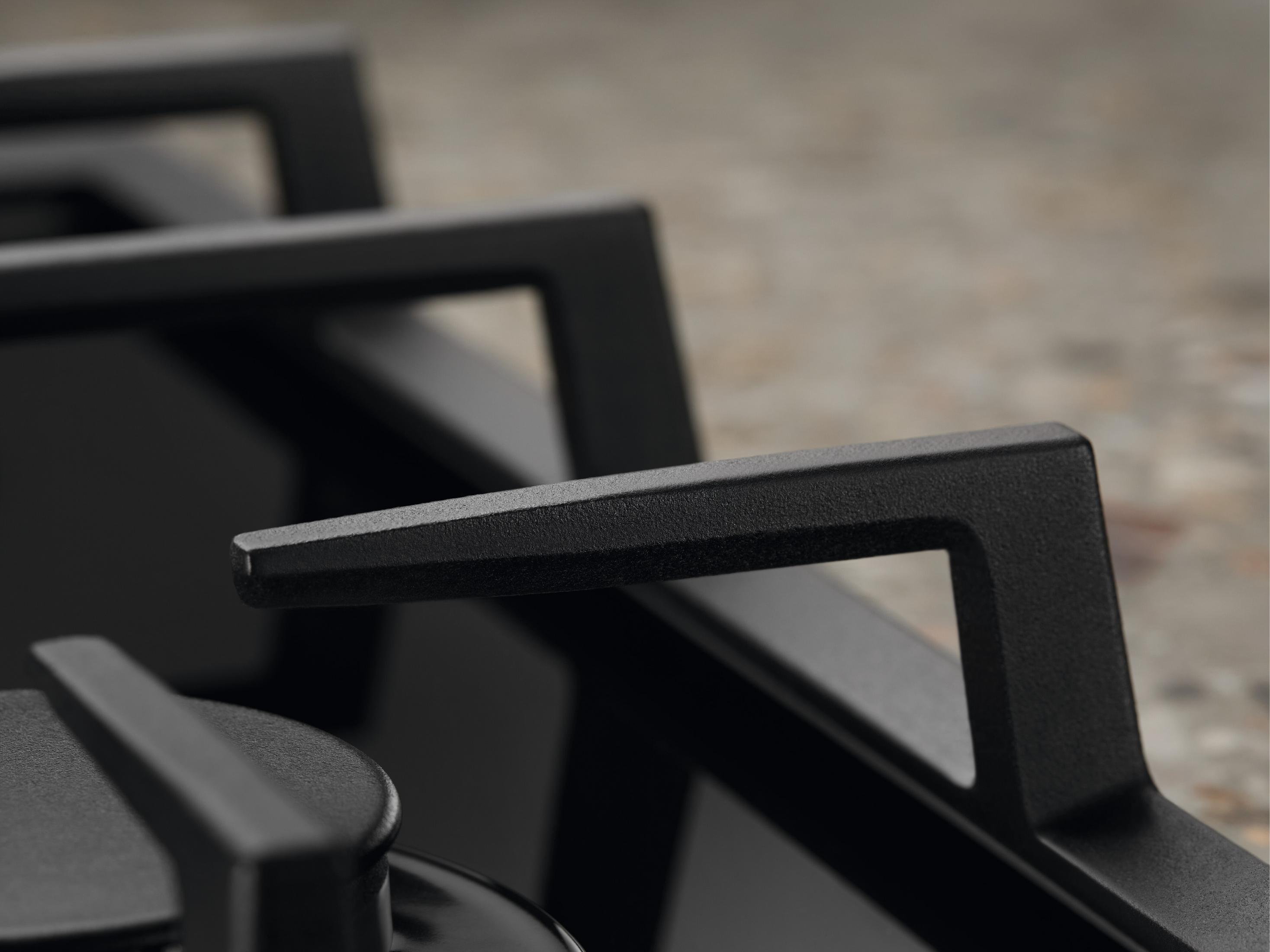 Zbliżenie czarnej kuchenki gazowej z żeliwnymi podparciami garnków i gładką powierzchnią.