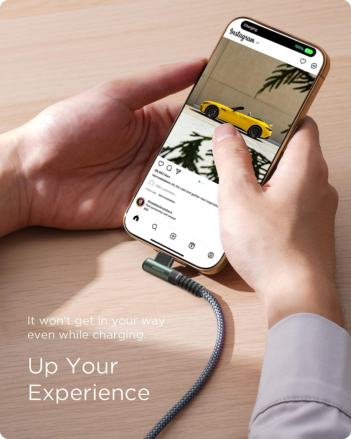 Dłoń trzyma telefon z Instagramem i żółtym samochodem. Podłączony jest kabel ładujący.