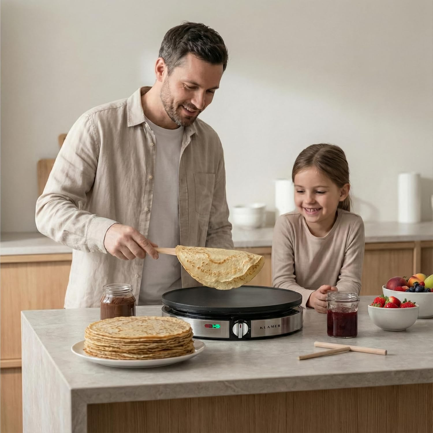 Mann und Kind backen Crêpes in der Küche. Ein Stapel Crêpes liegt auf einem Teller.