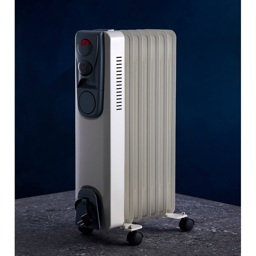 Ein weißer Ölradiator mit Rädern und Bedienelementen auf einem dunklen Tisch.
